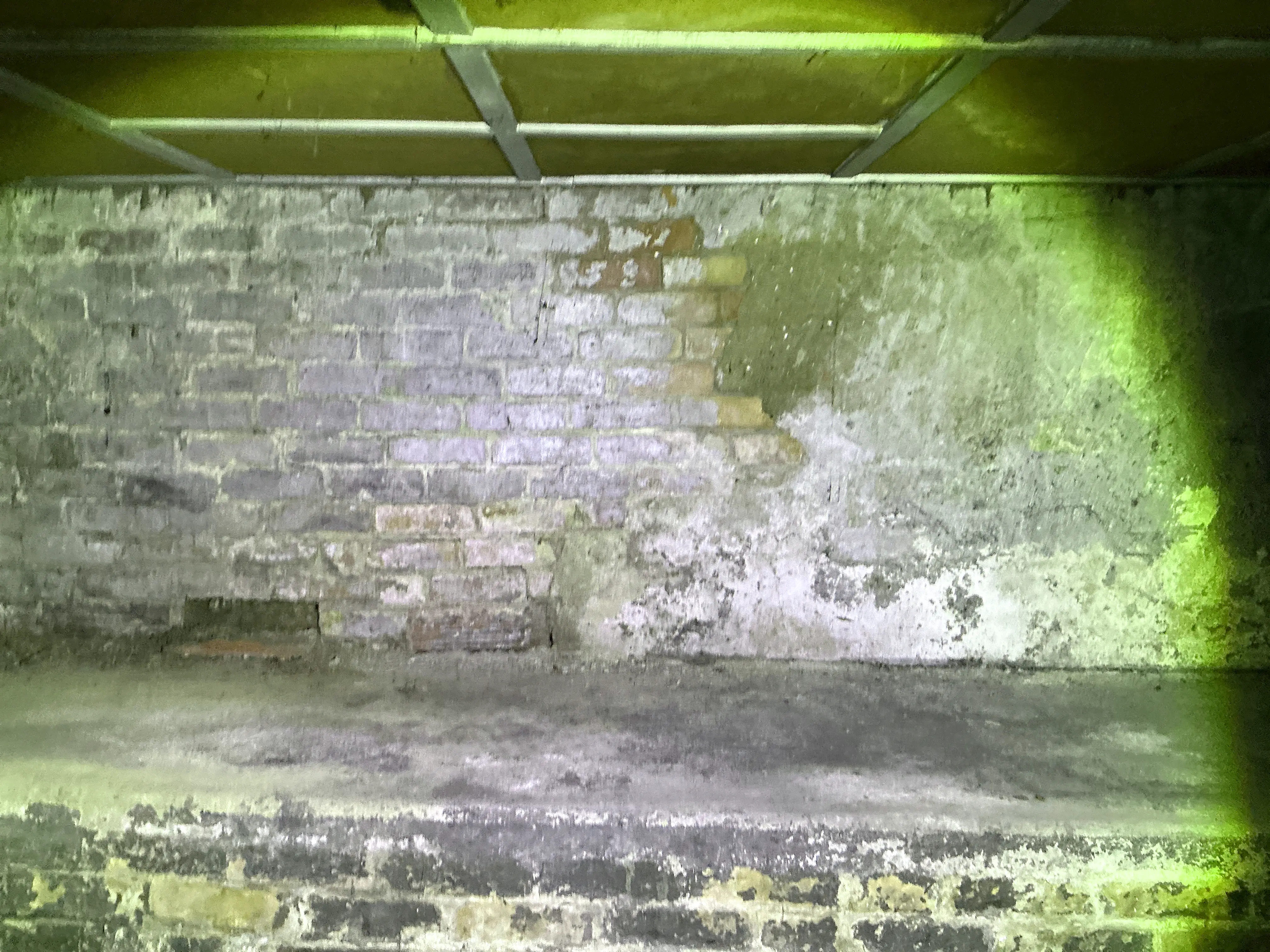 Exposed brick foundation wall with damaged plaster render in a home crawl space 2026-08-17