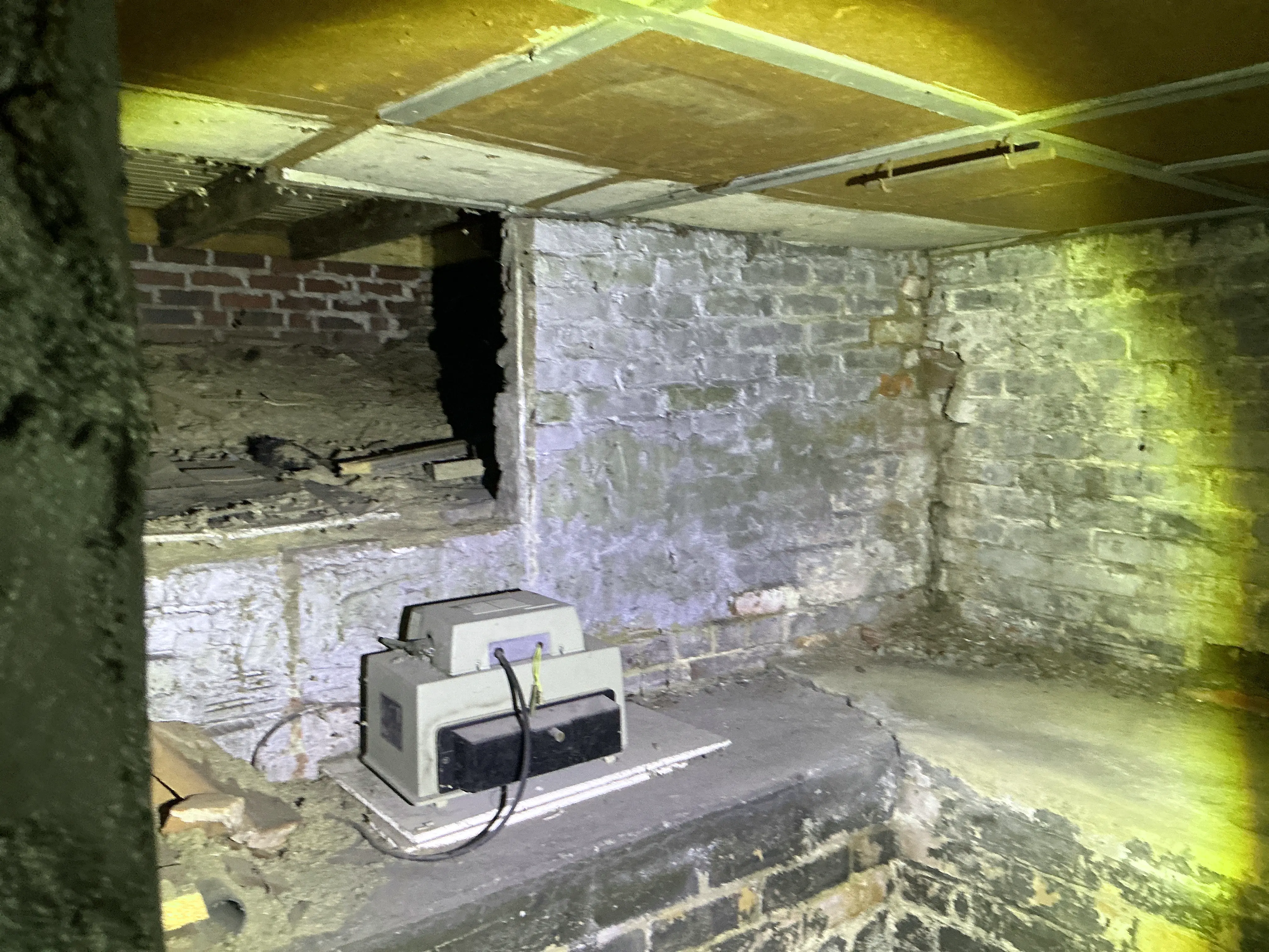 Abandoned electrical device sitting inside a crawlspace with exposed brick walls during lead test 2026-08-05