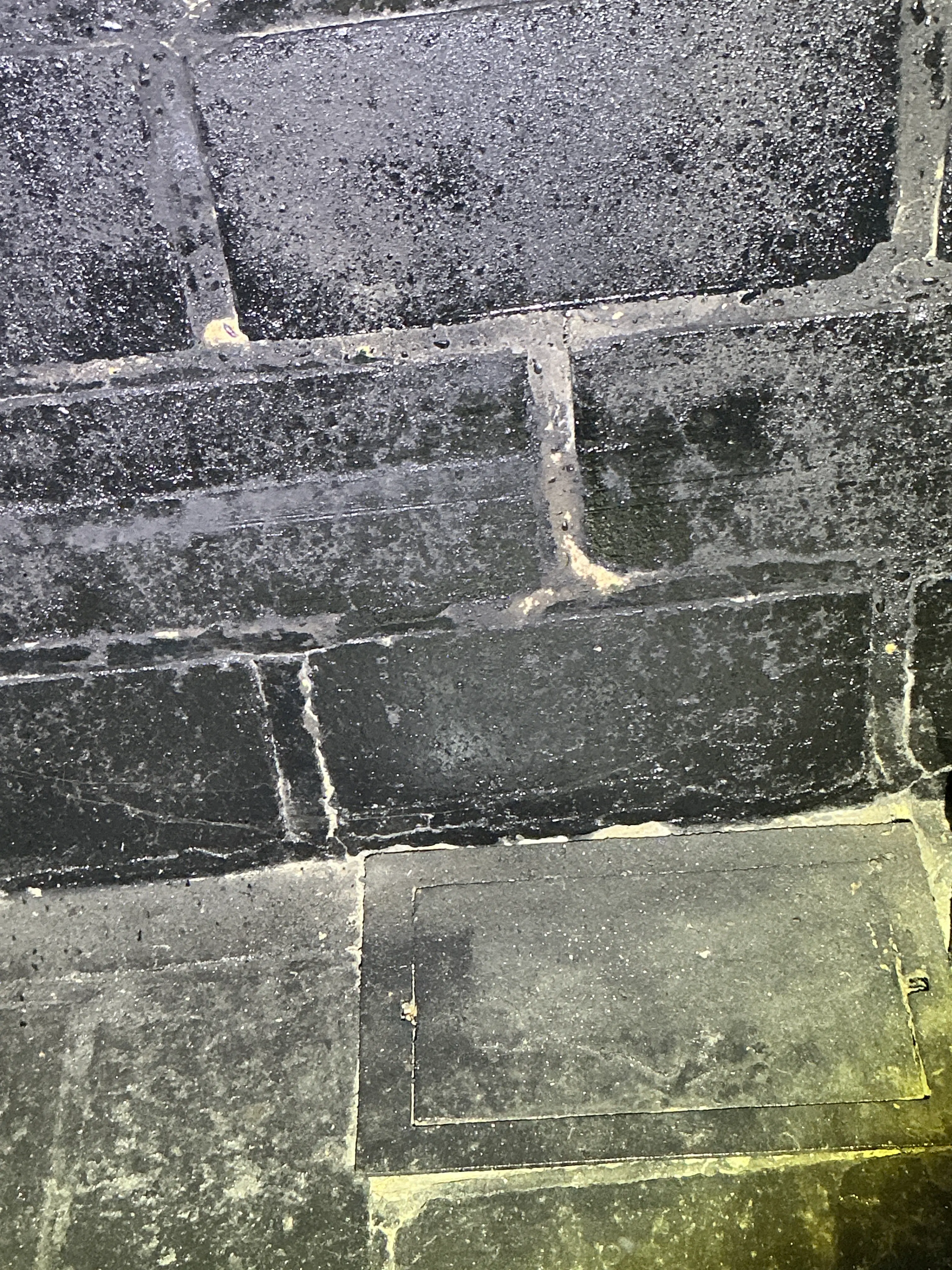 Embedded utility access cover in slate floor tiles during a home inspection. 2026-07-05
