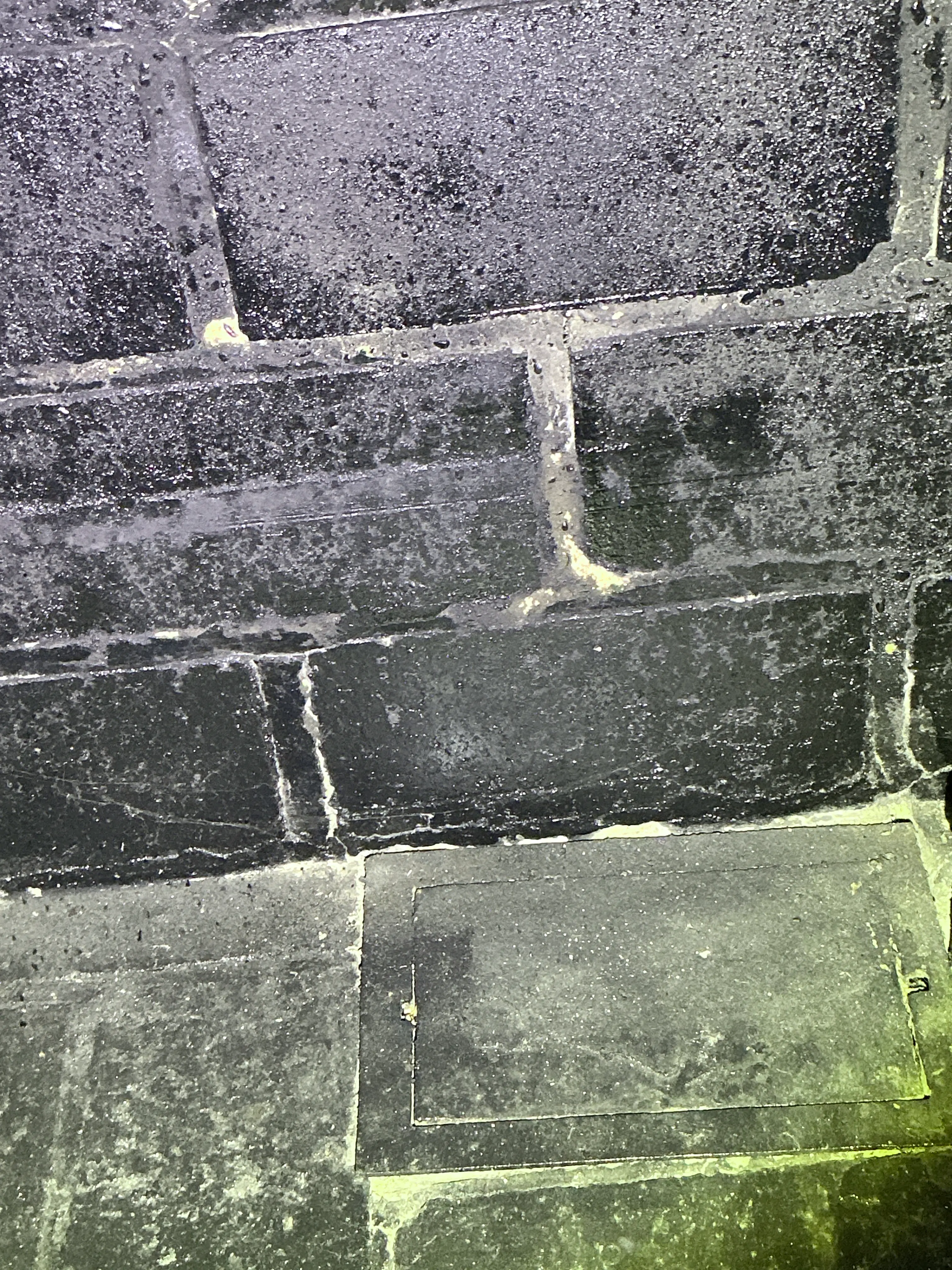 Embedded utility access cover in slate floor tiles during a mold testing. 2026-07-17