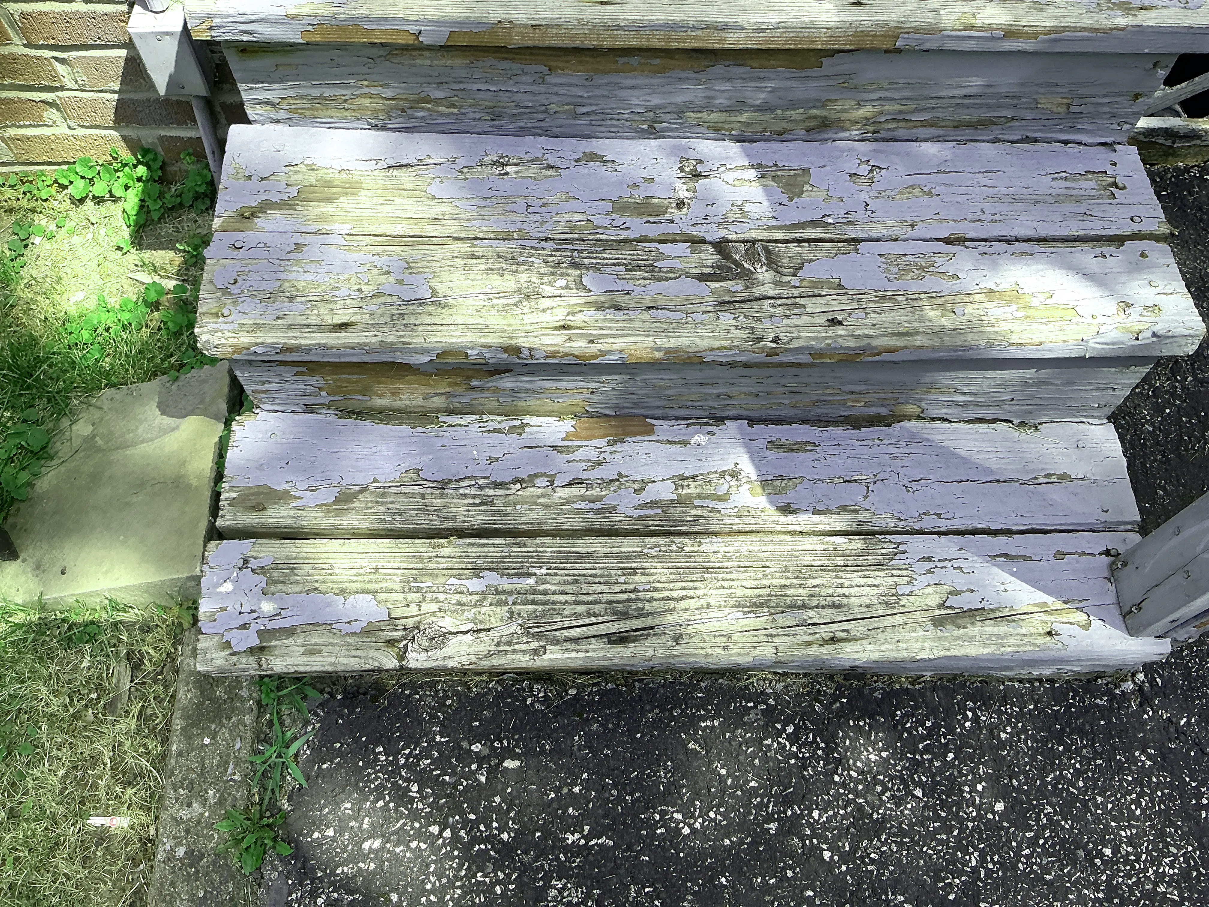 Peeling blue paint on weathered exterior wooden stair treads during a home inspection 2026-08-04