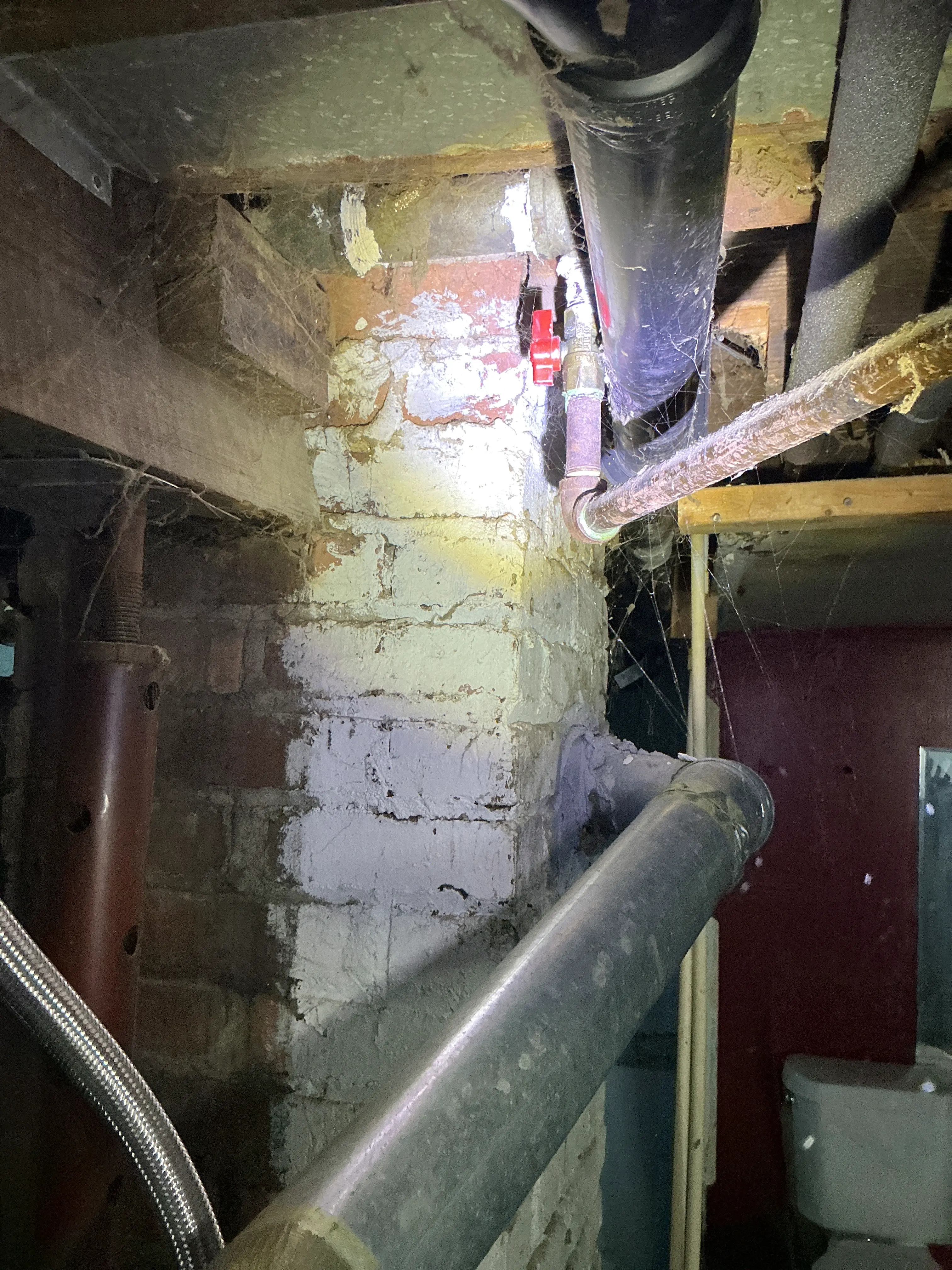 Exposed plumbing pipes, shutoff valve, and brick foundation wall in a basement during a home inspection 2026-08-07