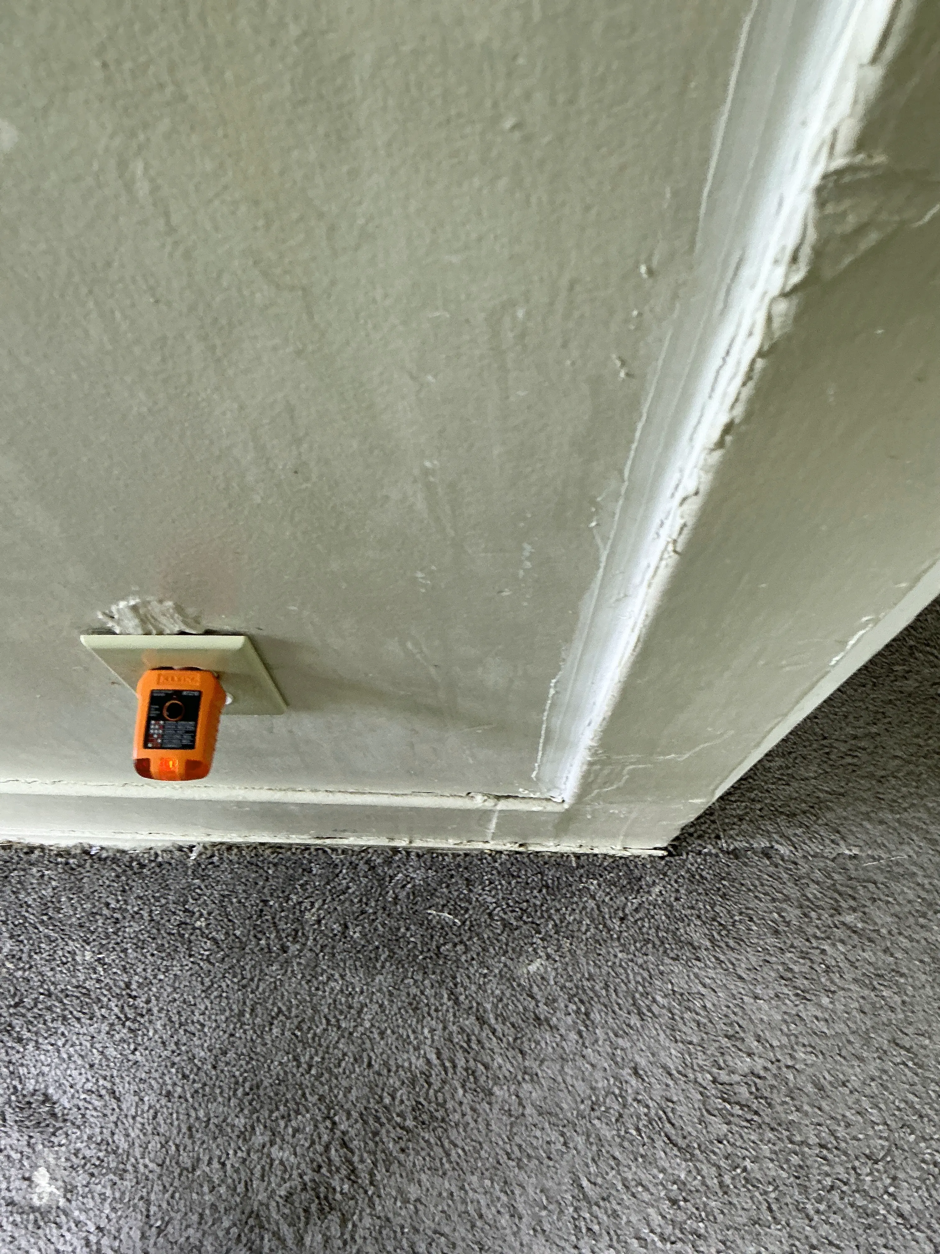 Electrical receptacle tester plugged into a low wall outlet near carpet during a lead inspection 2026-07-14