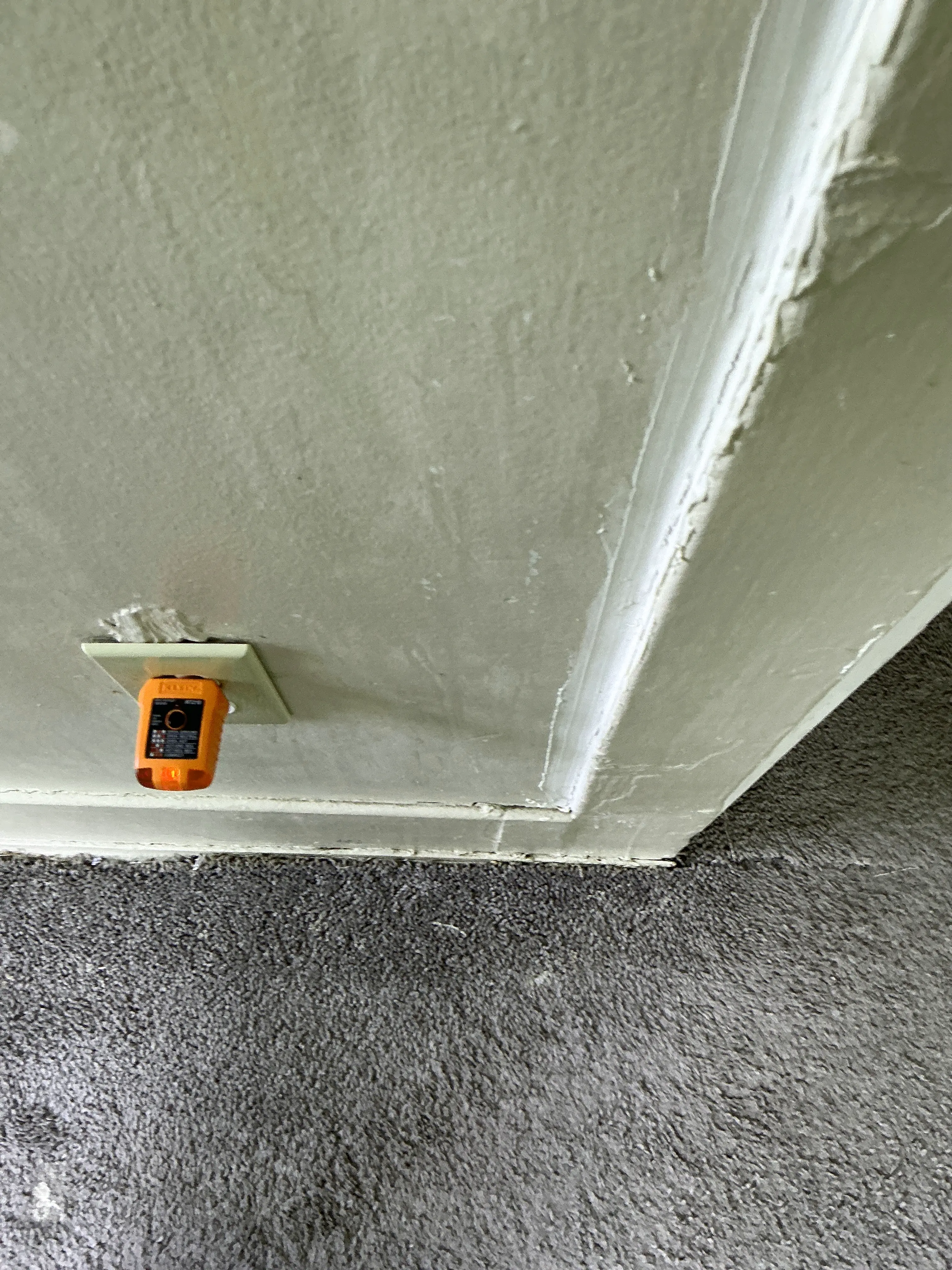 Electrical receptacle tester plugged into a low wall outlet near carpet during a general inspection 2026-08-02