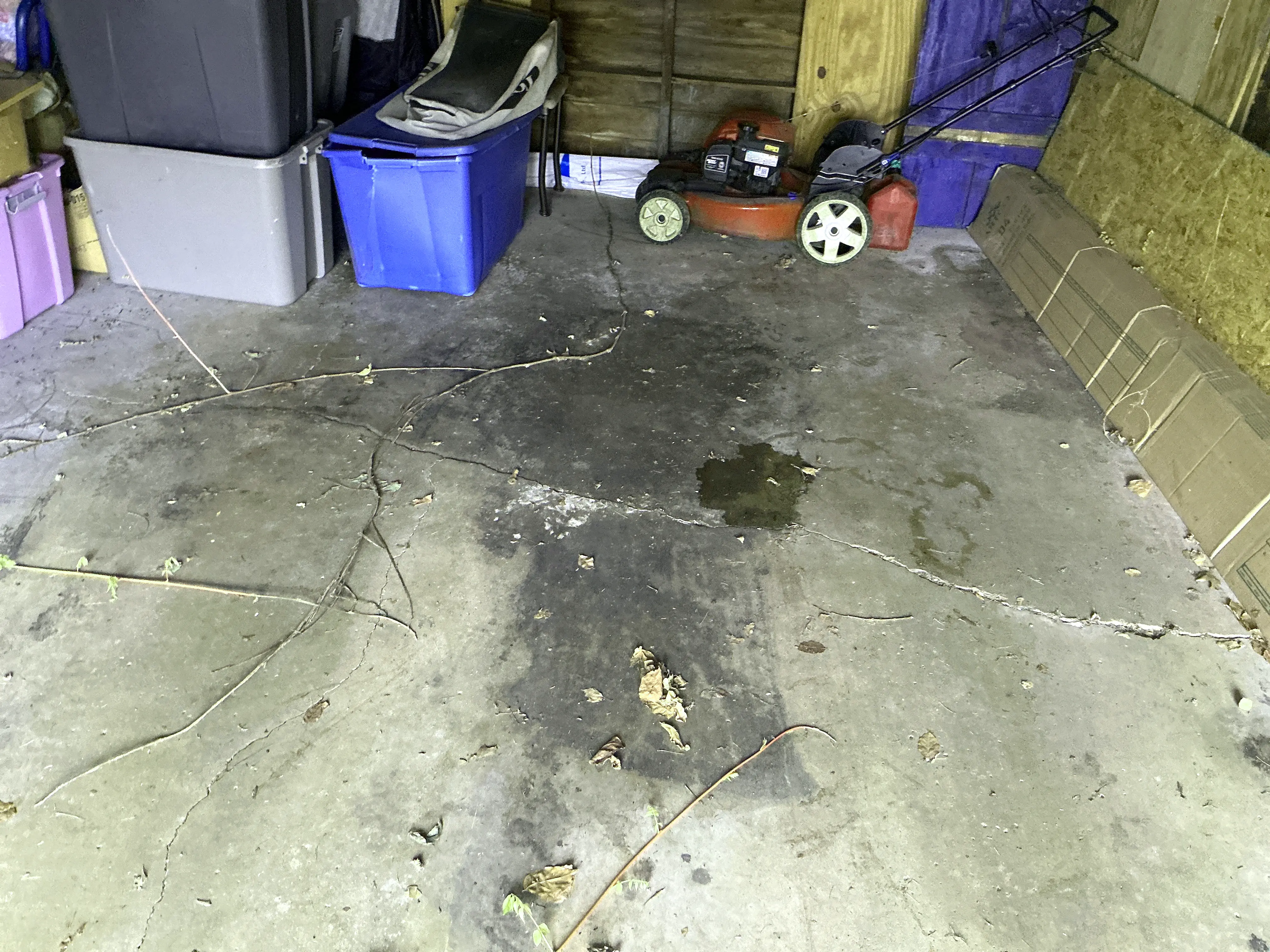 Garage floor inspection showing cracks and fluid stains on concrete slab. 2026-07-06