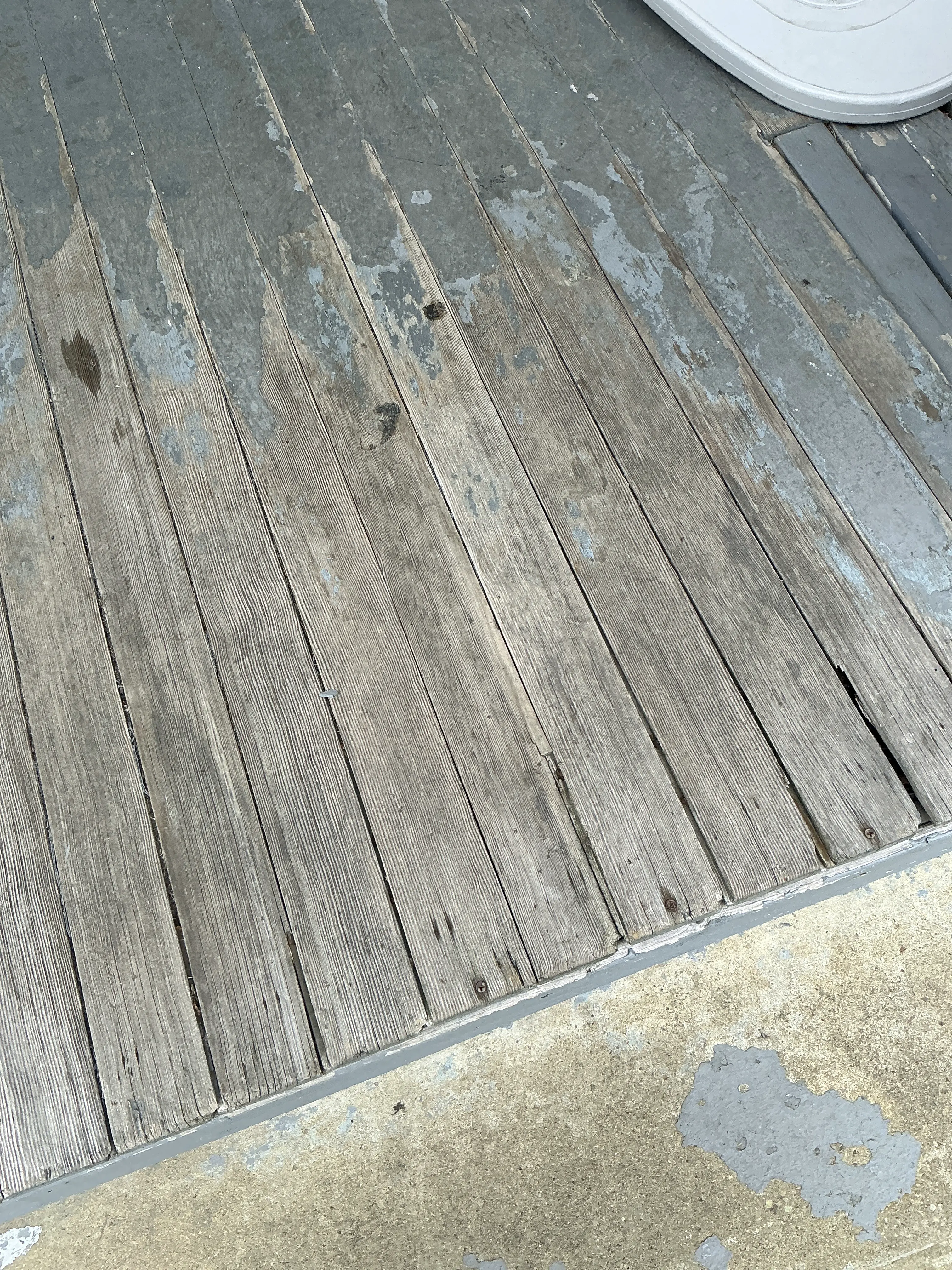 Peeling paint and weathered wooden deck boards in need of refinishing. 2026-07-16