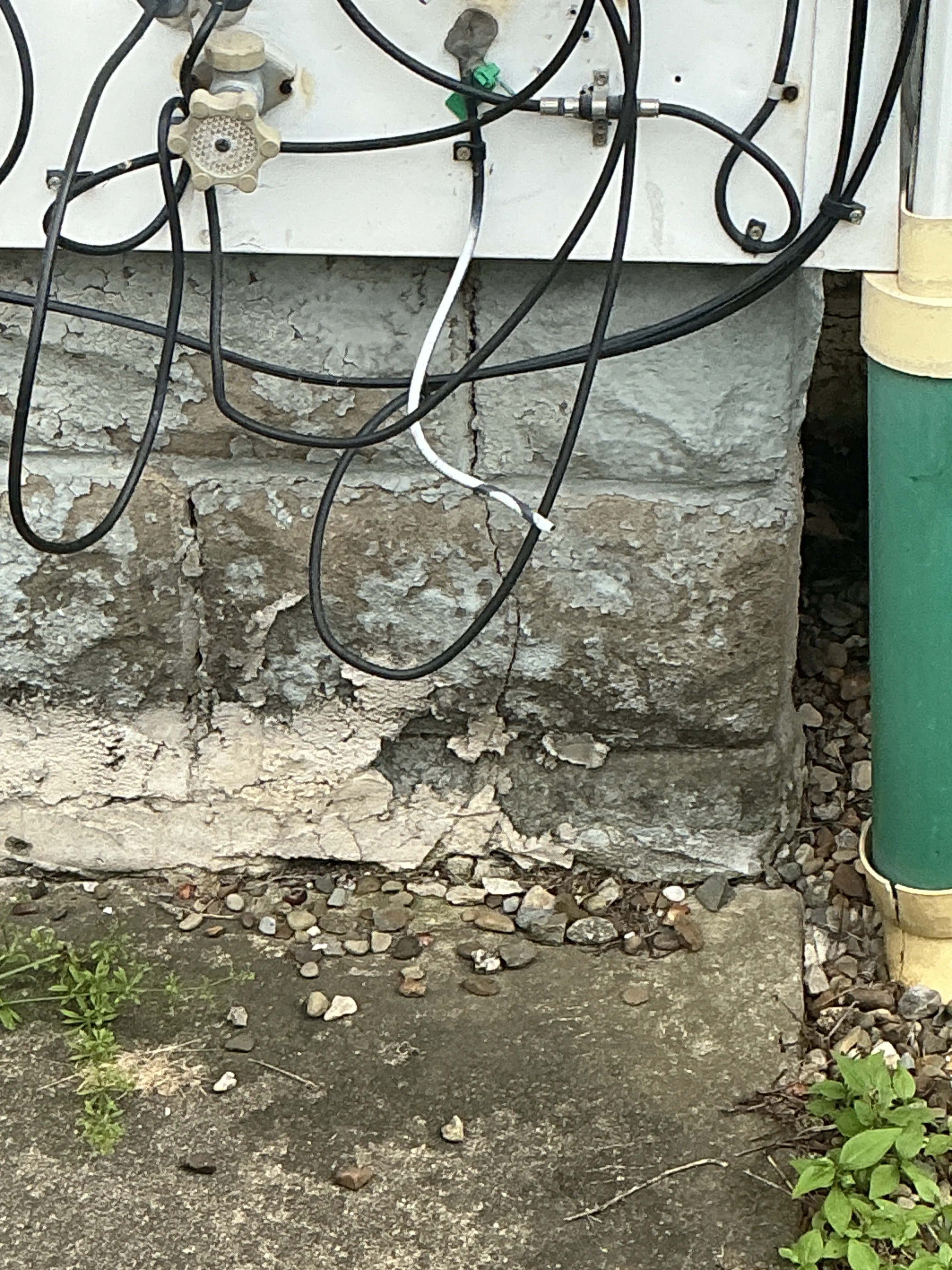 Deteriorated concrete foundation showing cracks and surface spalling near ground level 2026-07-20