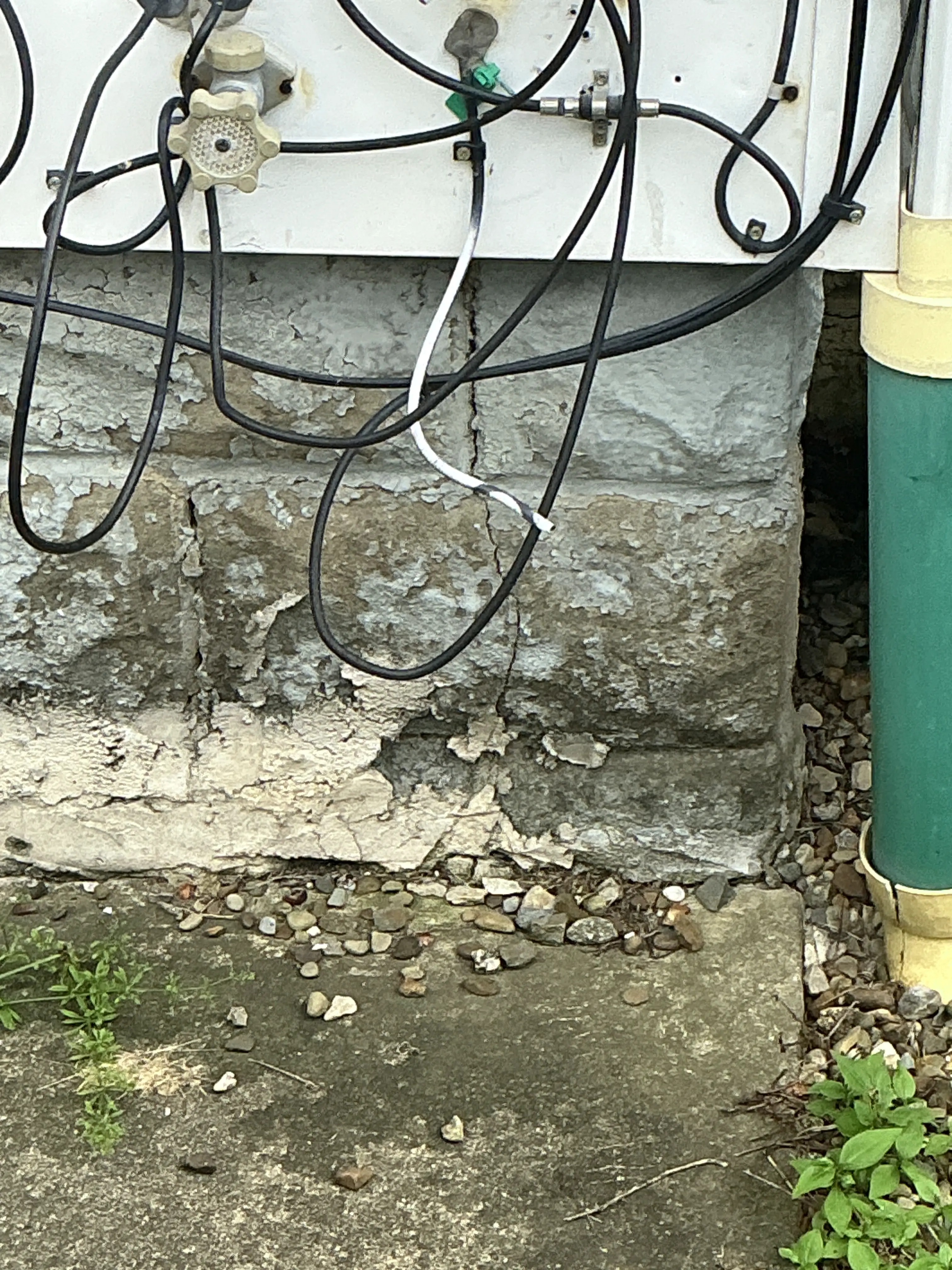 Deteriorated concrete foundation showing cracks and surface spalling near ground level 2026-07-24