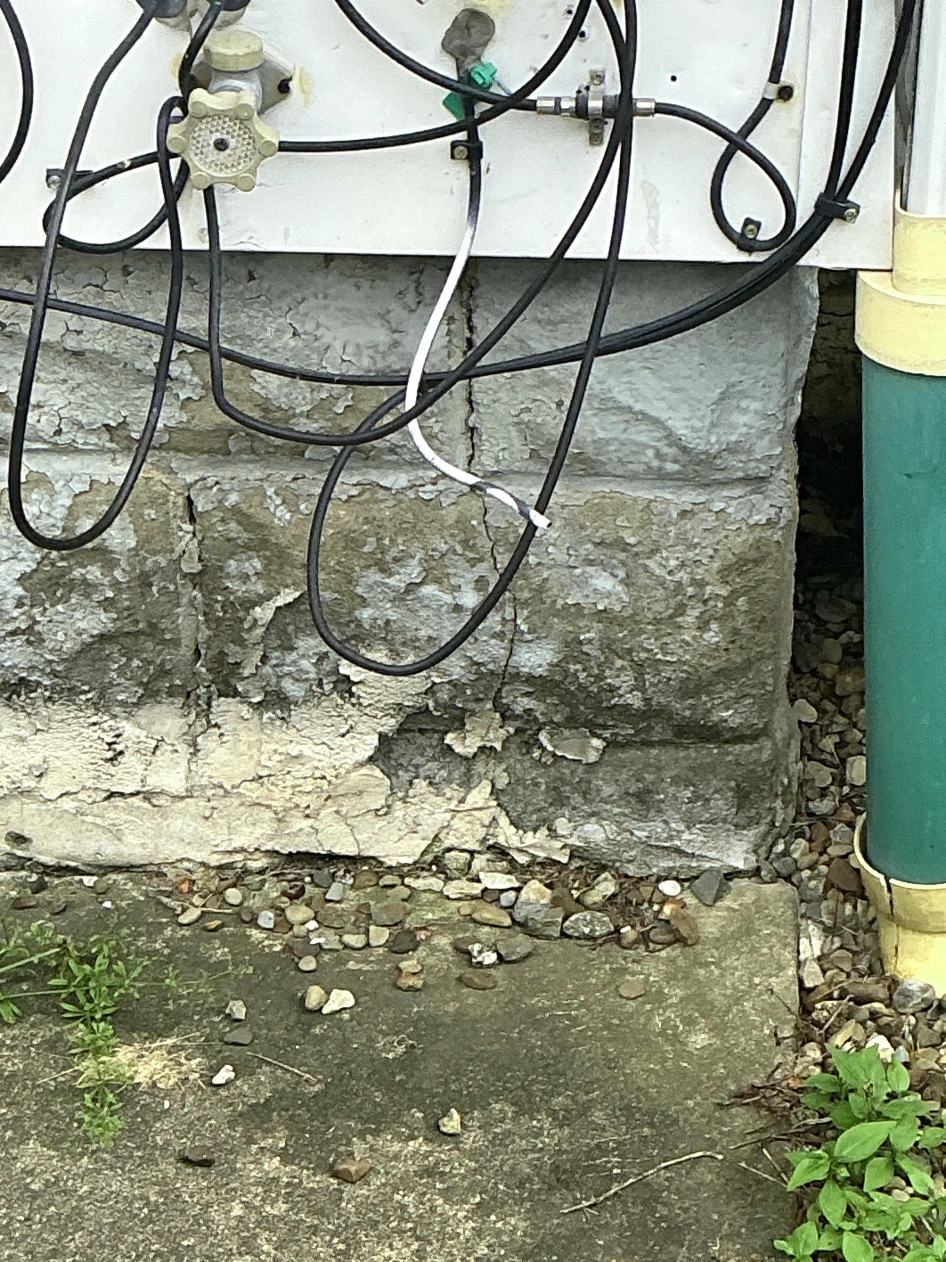 Deteriorated concrete foundation showing cracks and surface spalling near ground level 2026-08-23