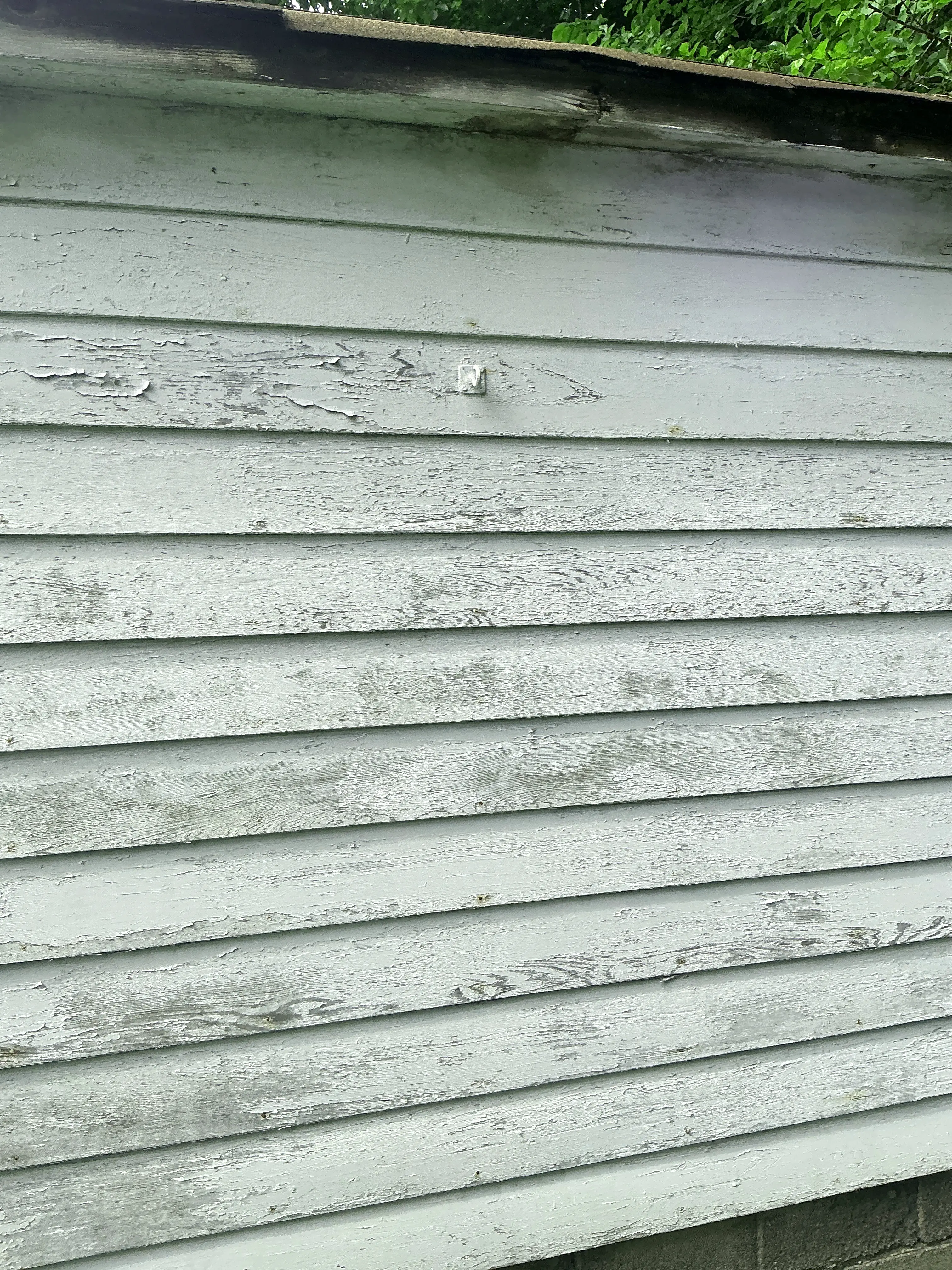 Peeling paint and weathered vertical wood siding on home exterior requiring maintenance 2026-08-25