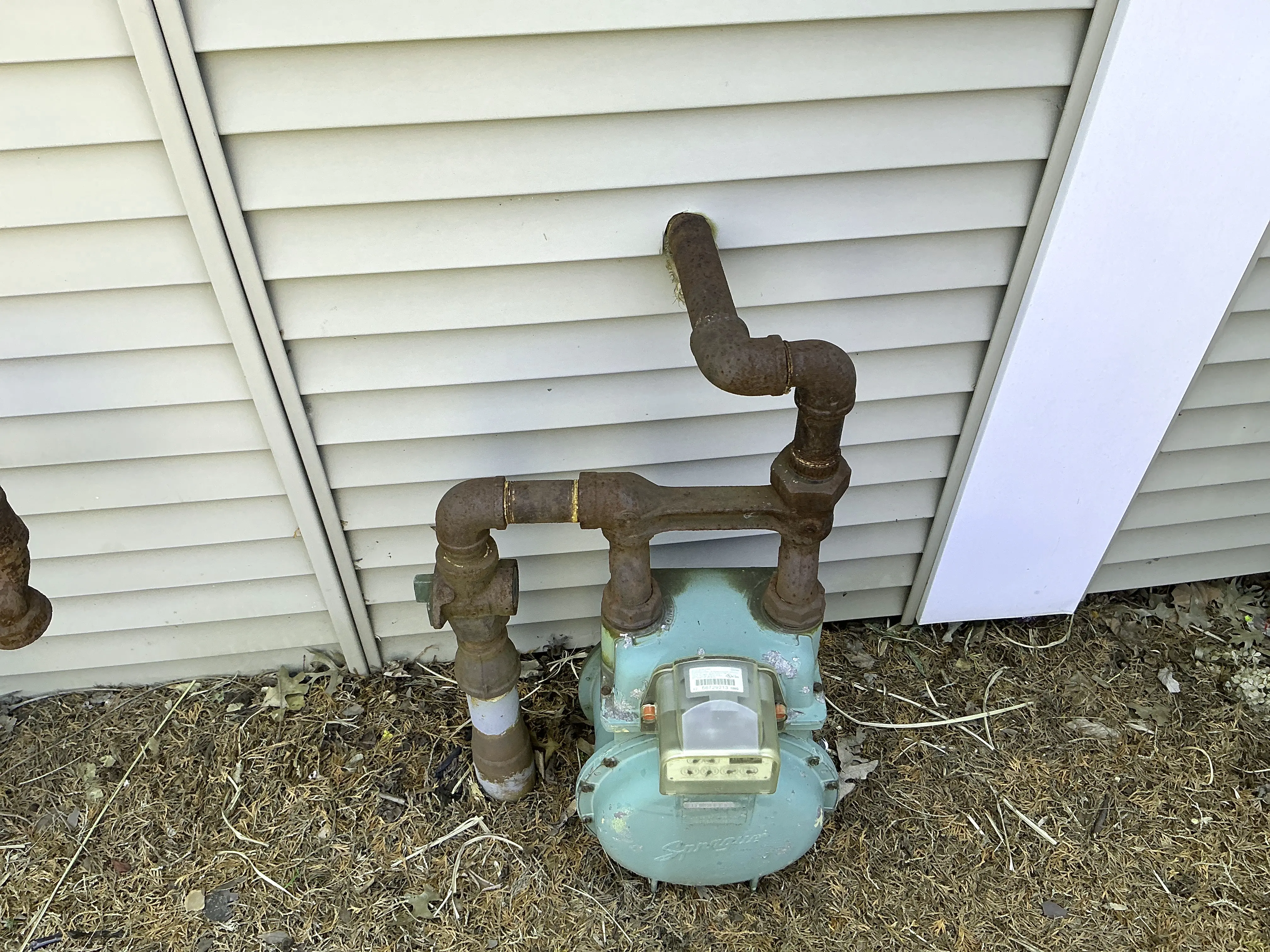 Rusted exterior gas meter piping against vinyl house siding 2026-08-20
