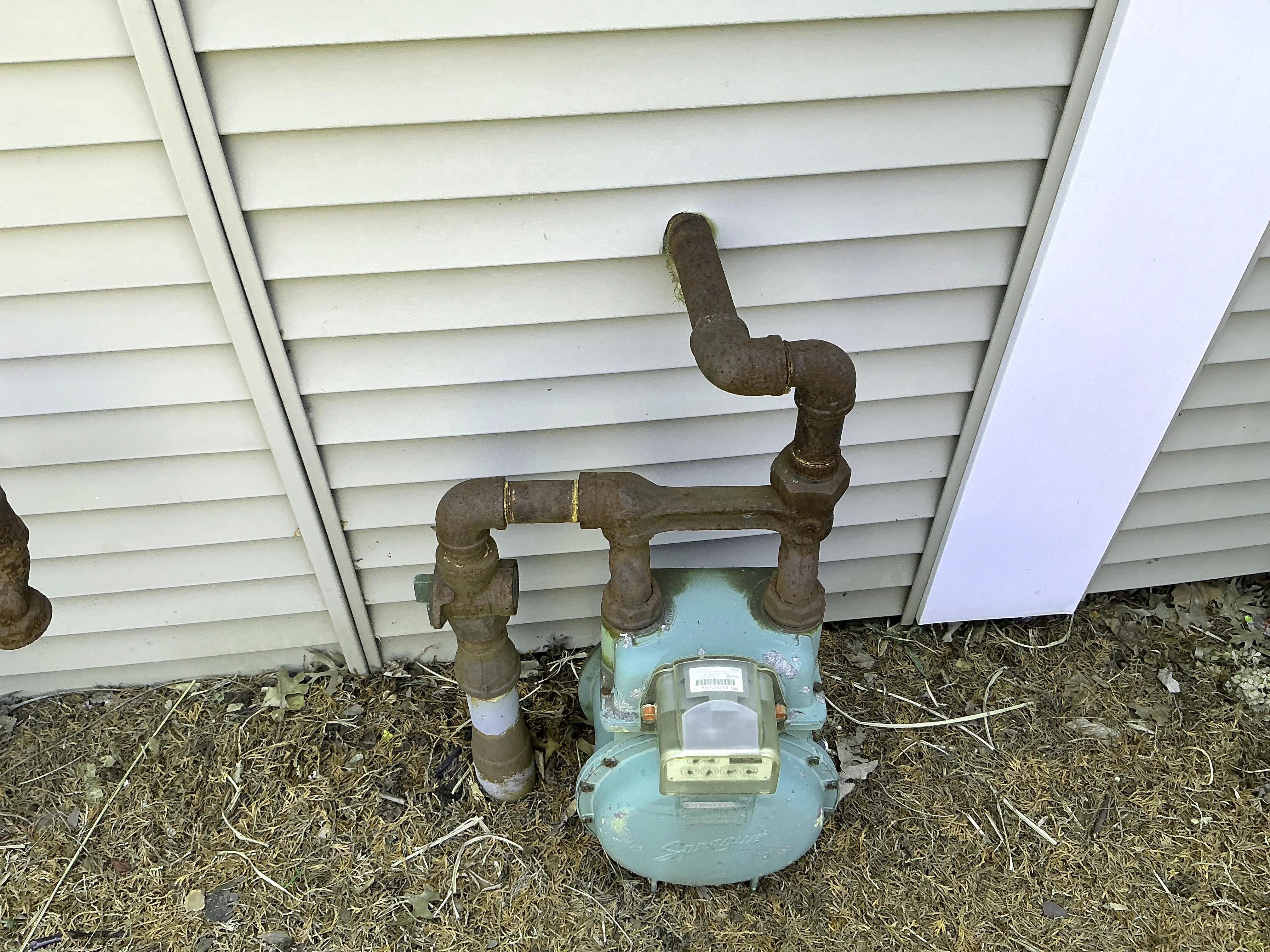 Rusted exterior gas meter piping against vinyl house siding 2026-08-30