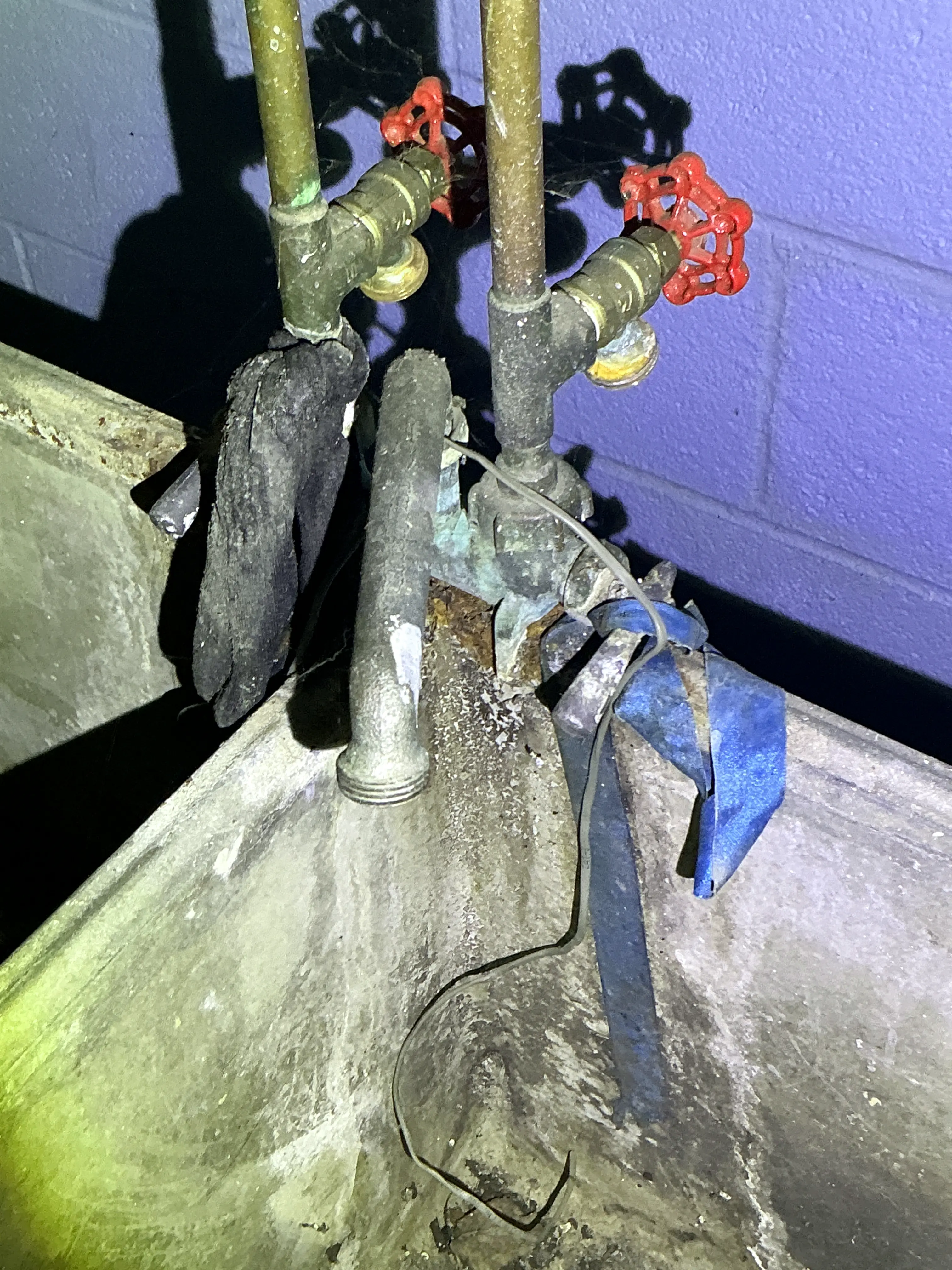 Corroded plumbing pipes and improper grounding wire under utility sink 2026-07-21