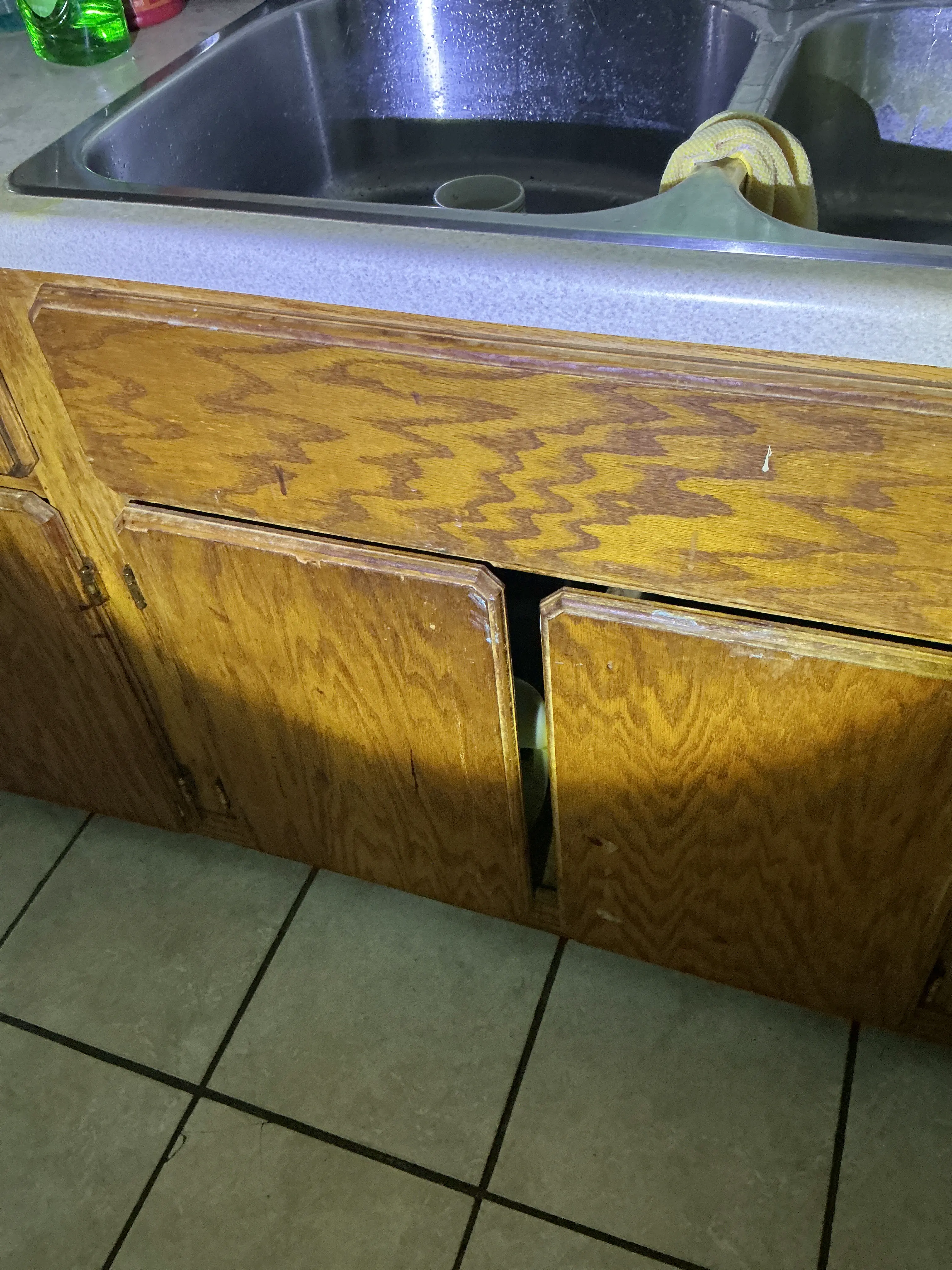 Damaged and misaligned wooden kitchen cabinet doors below sink during lead test 2026-07-08