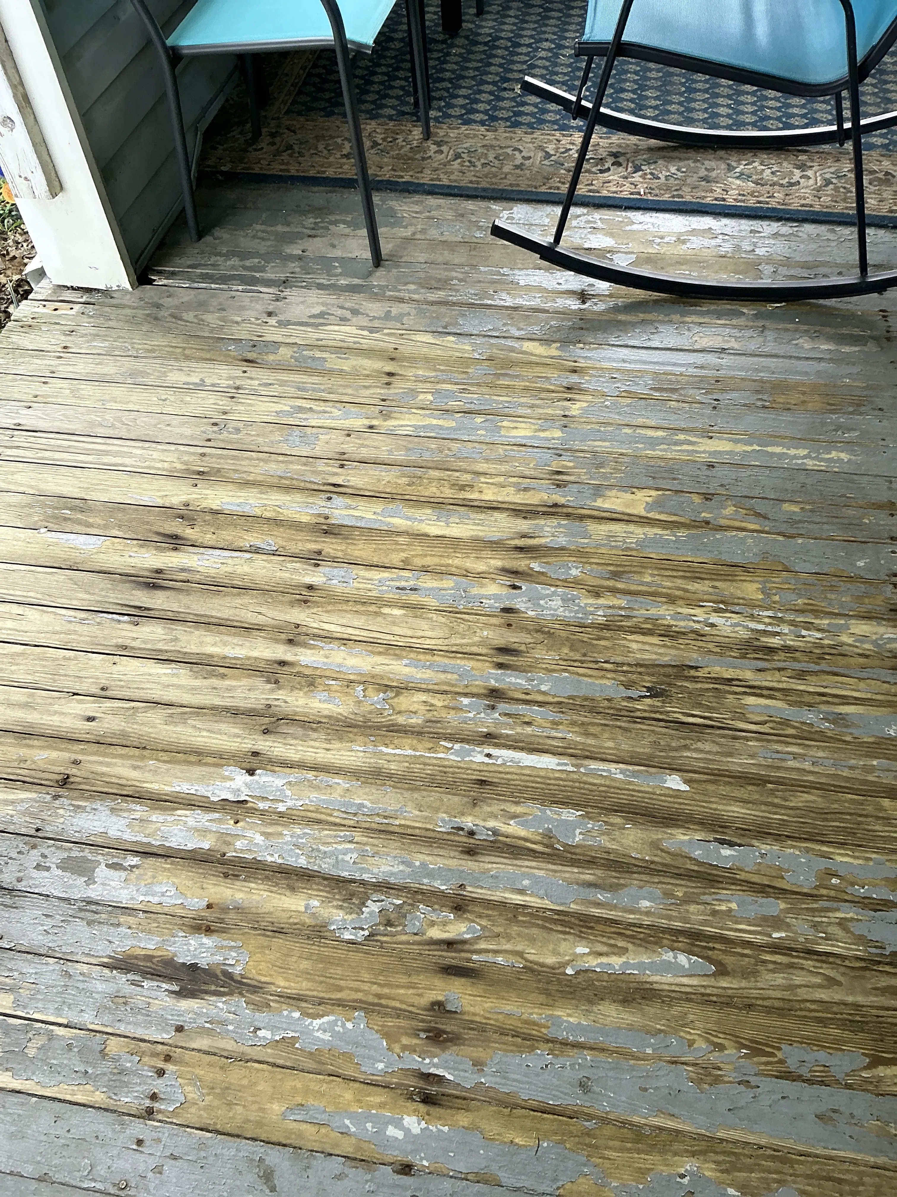 Severely peeling paint on a wooden deck floor exposing worn wood 2026-08-14