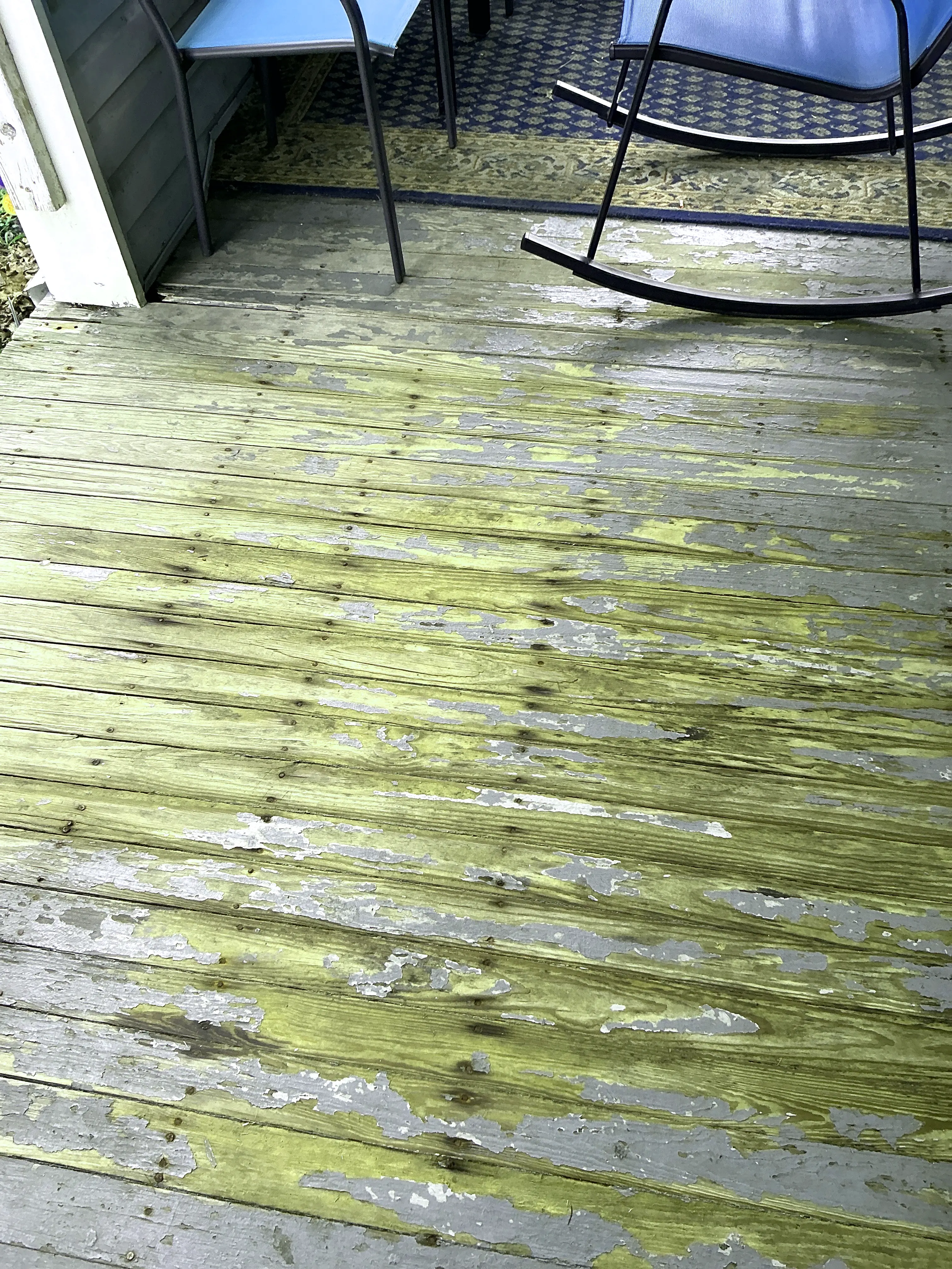 Severely peeling paint on a wooden deck floor exposing worn wood 2026-07-06