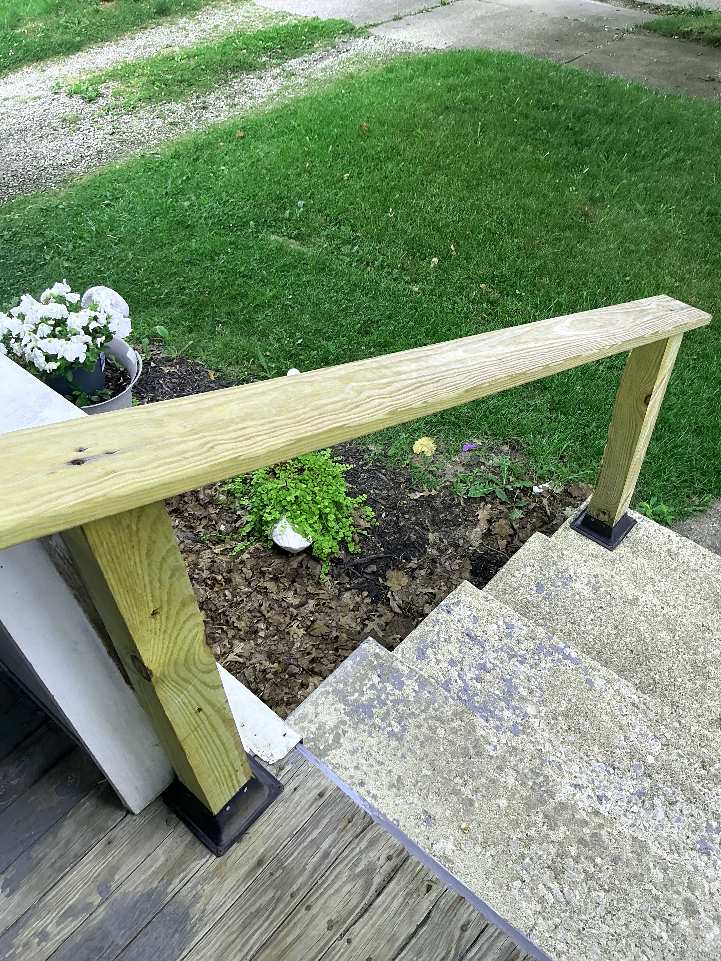 Wooden handrail mounted near exterior concrete stairs and porch deck 2026-08-02