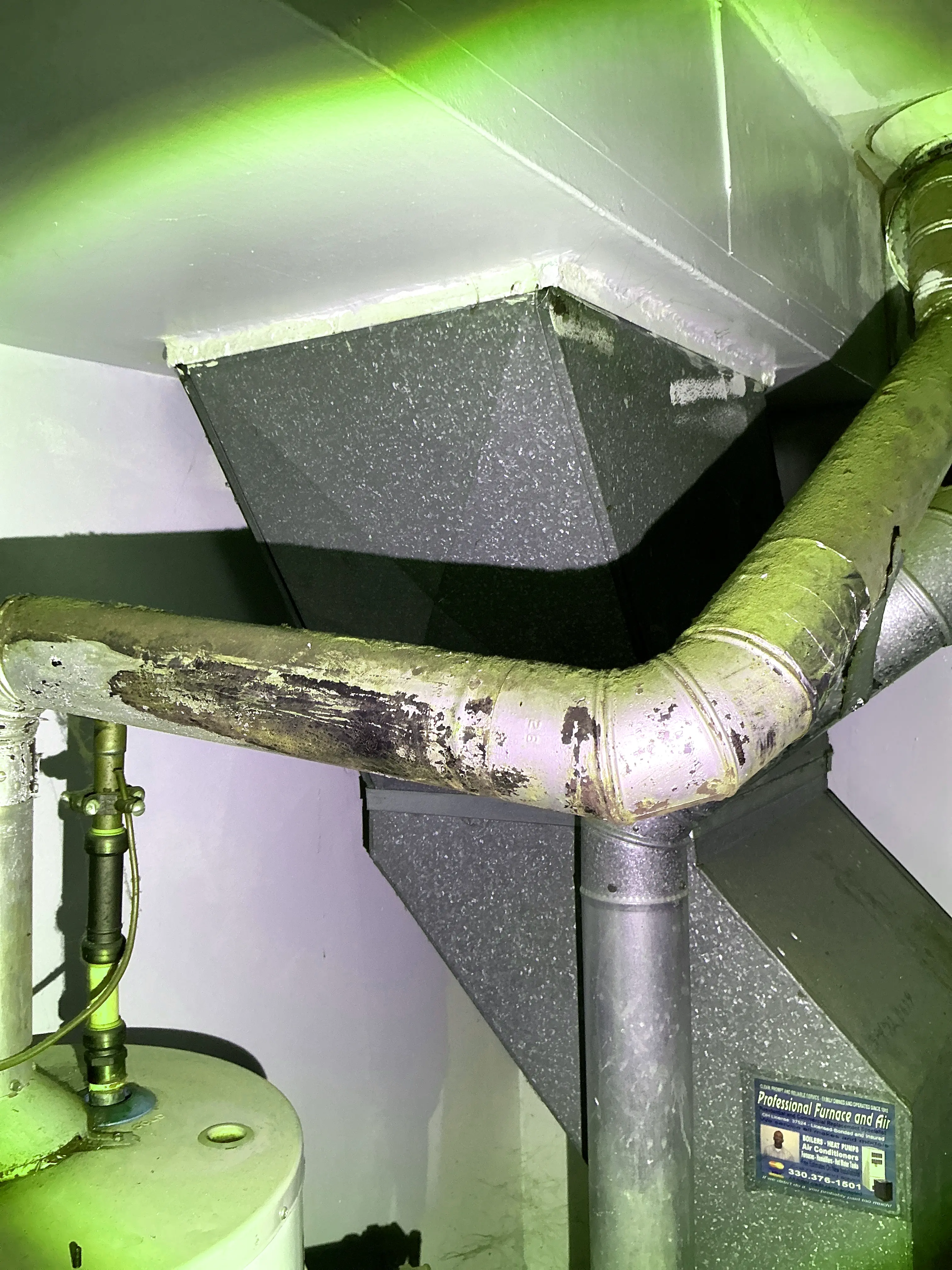 Corroded and discolored metal flue pipe connected to an HVAC duct system in a home basement. 2026-08-07