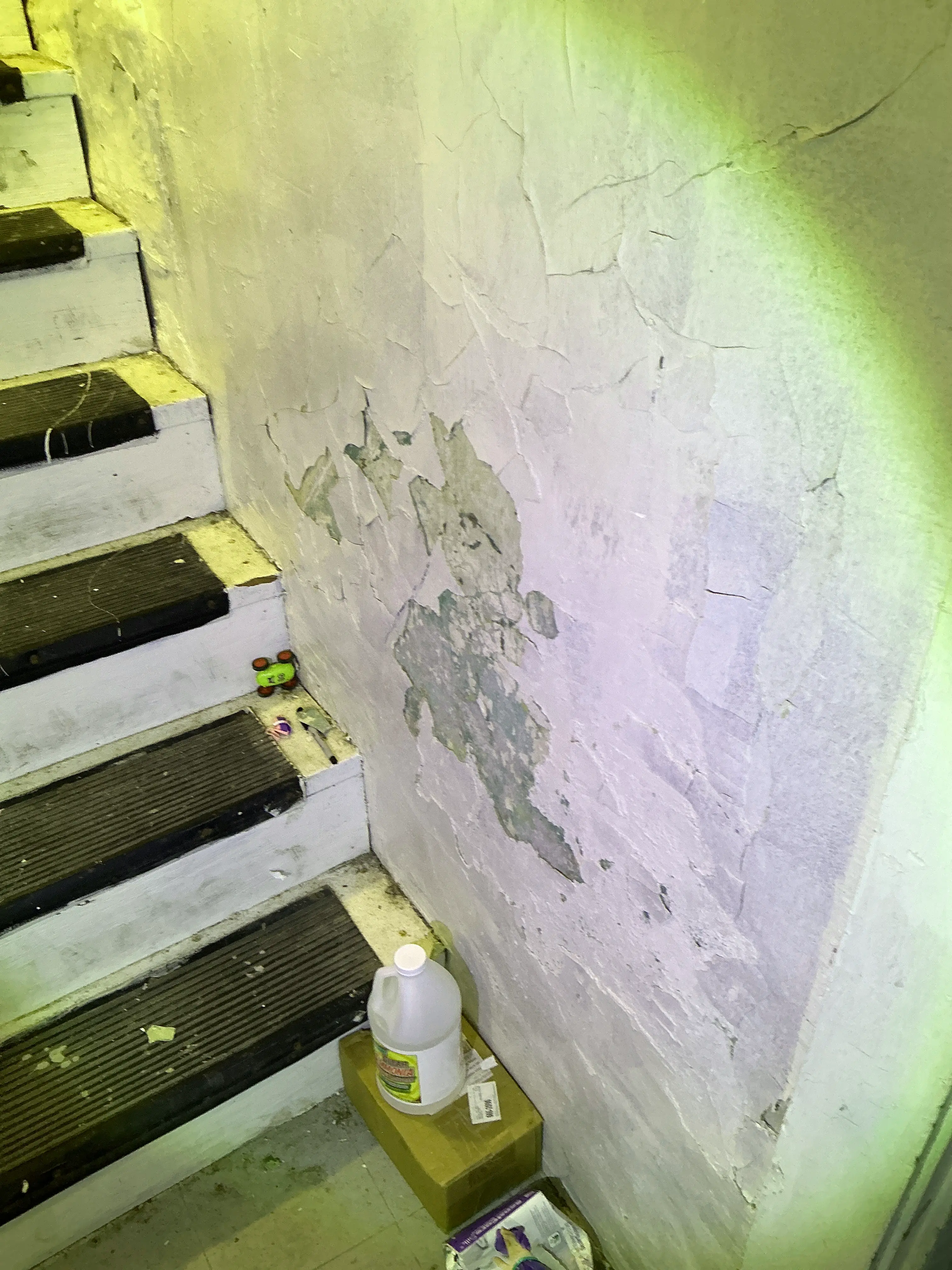 Severe paint peeling and plaster damage on wall above staircase 2026-07-14