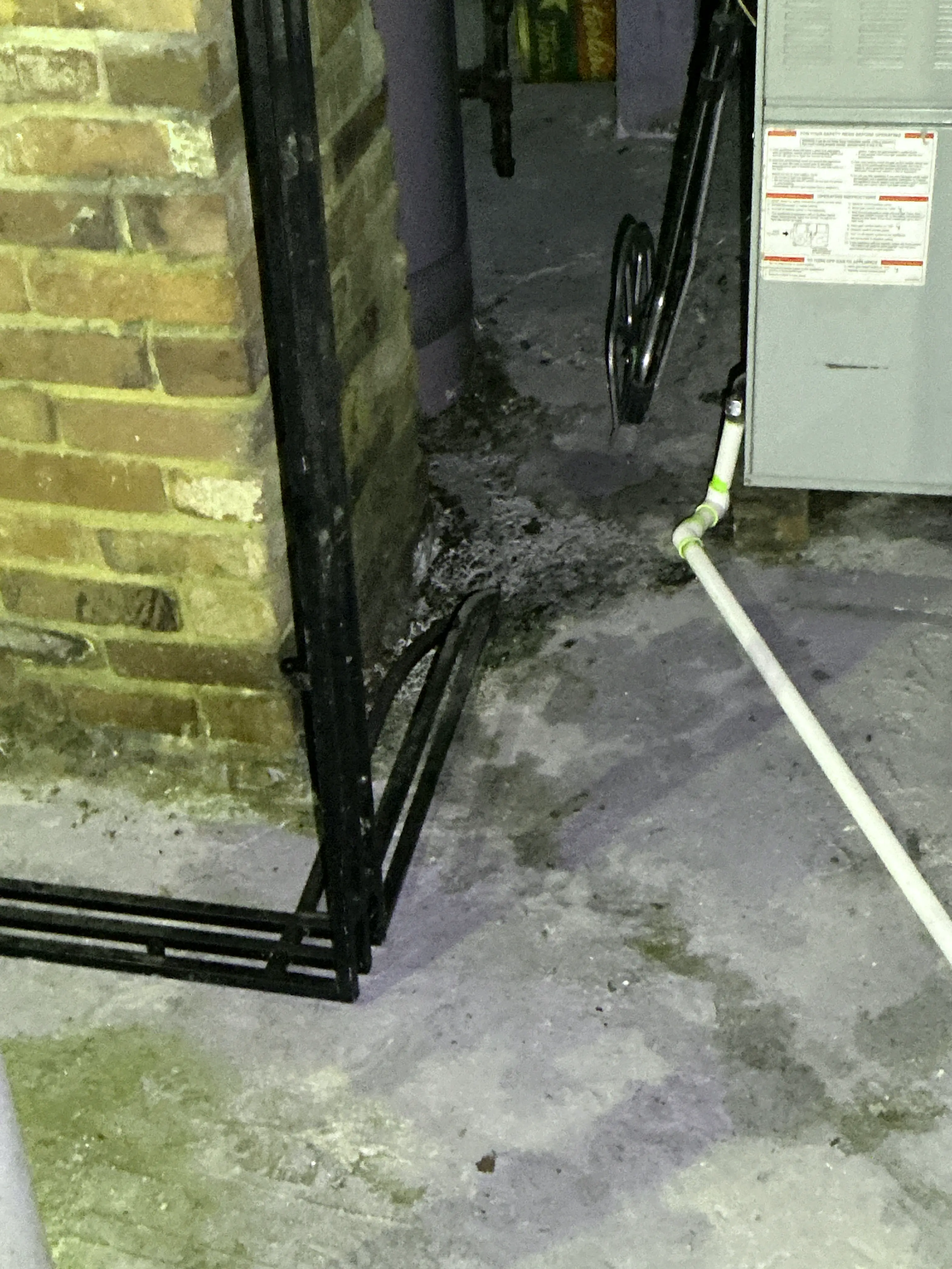 Moisture staining on basement concrete wall behind HVAC equipment during home inspection. 2026-08-14