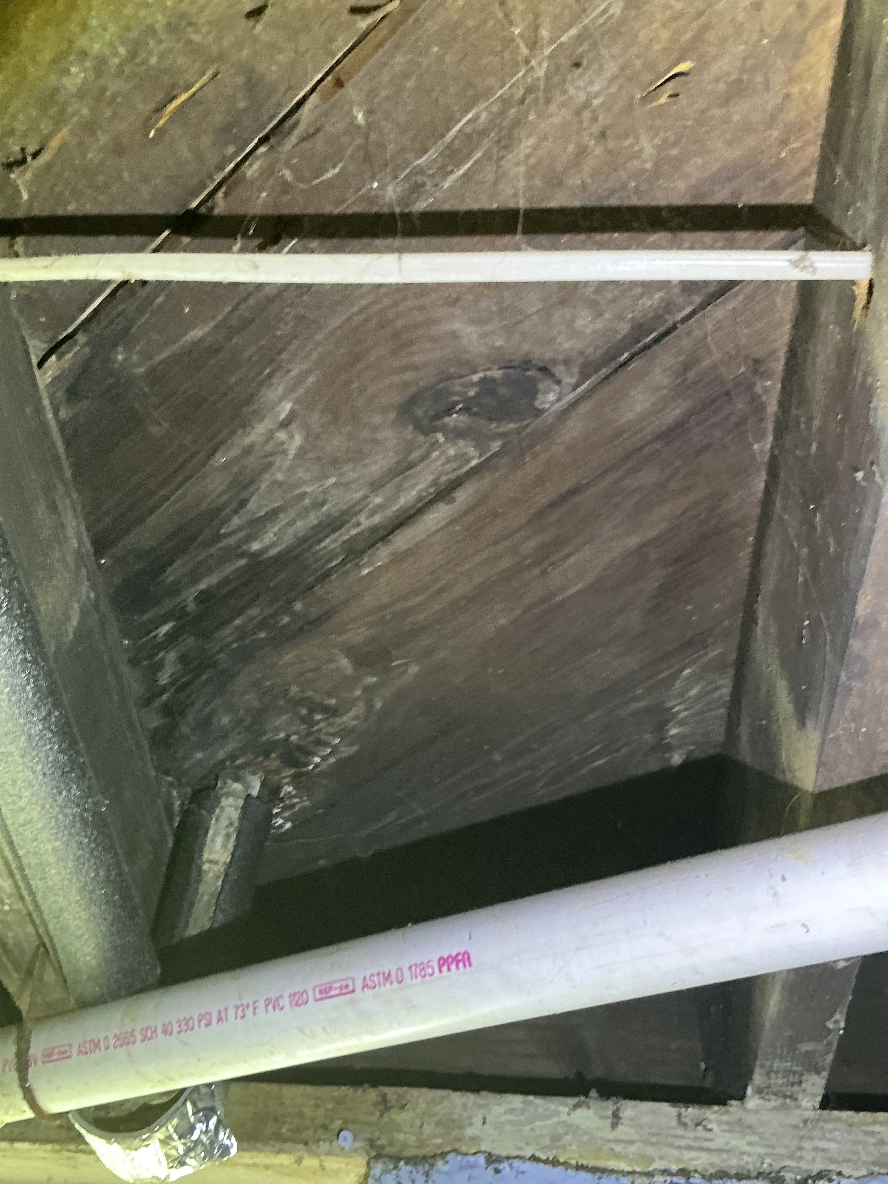 PVC plumbing pipe and subfloor boards in crawl space frame during home inspection 2026-07-07