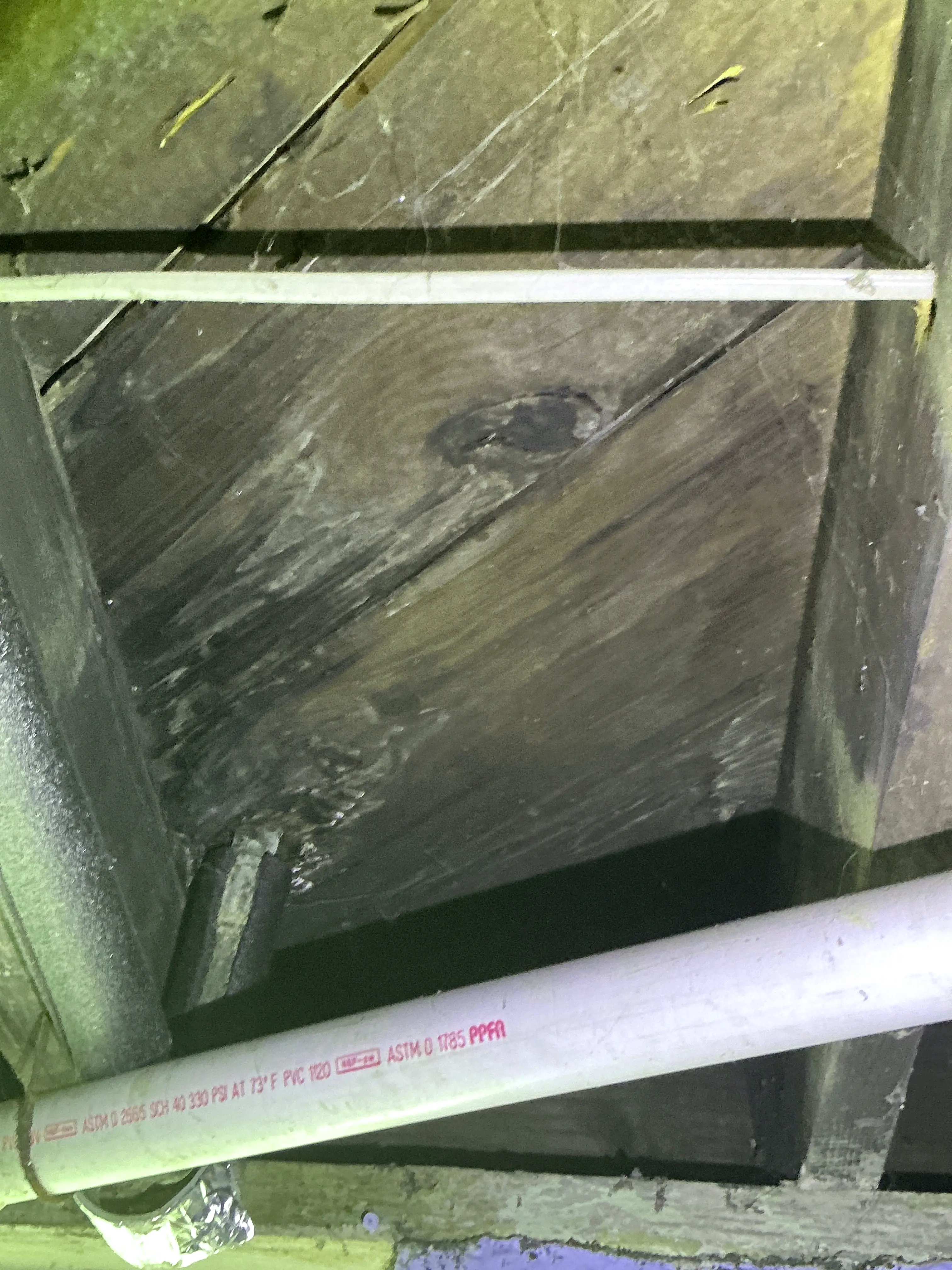 PVC plumbing pipe and subfloor boards in crawl space frame during home inspection 2026-07-05