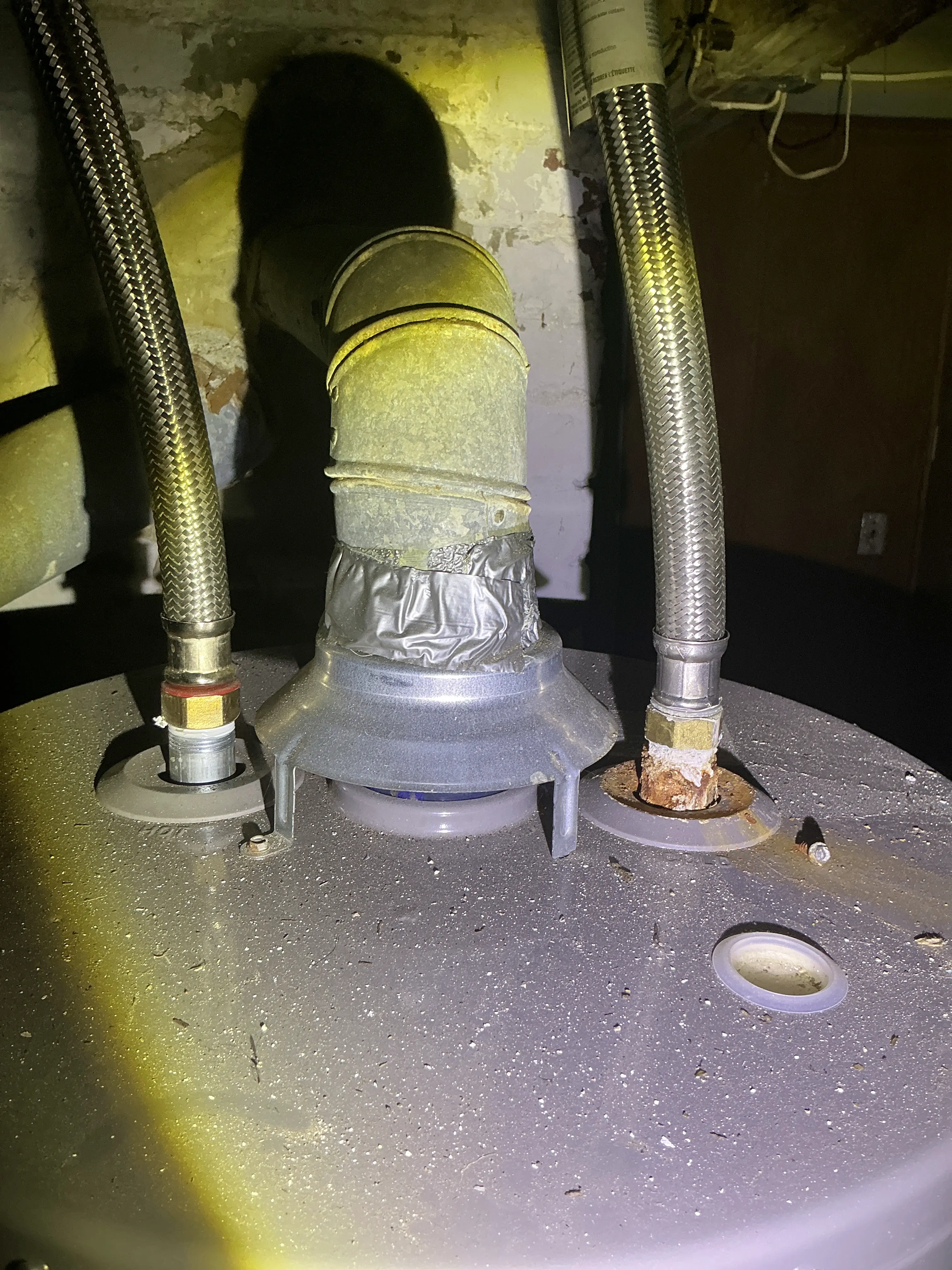 Corroded plumbing connection and taped vent pipe on top of a gas water heater 2026-07-10