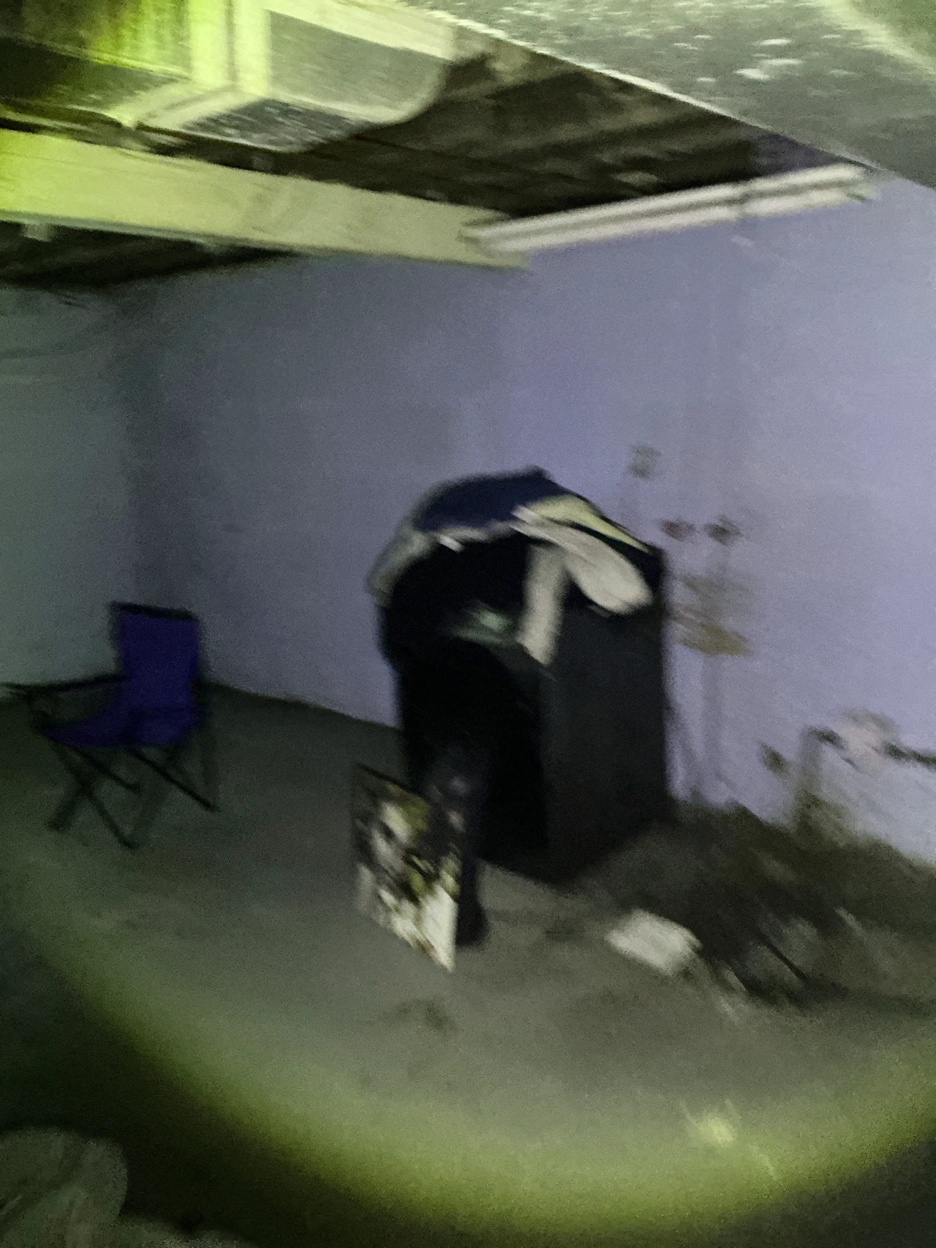 Flashlight beam illuminating a dark basement room with furniture during mold inspection 2026-07-19