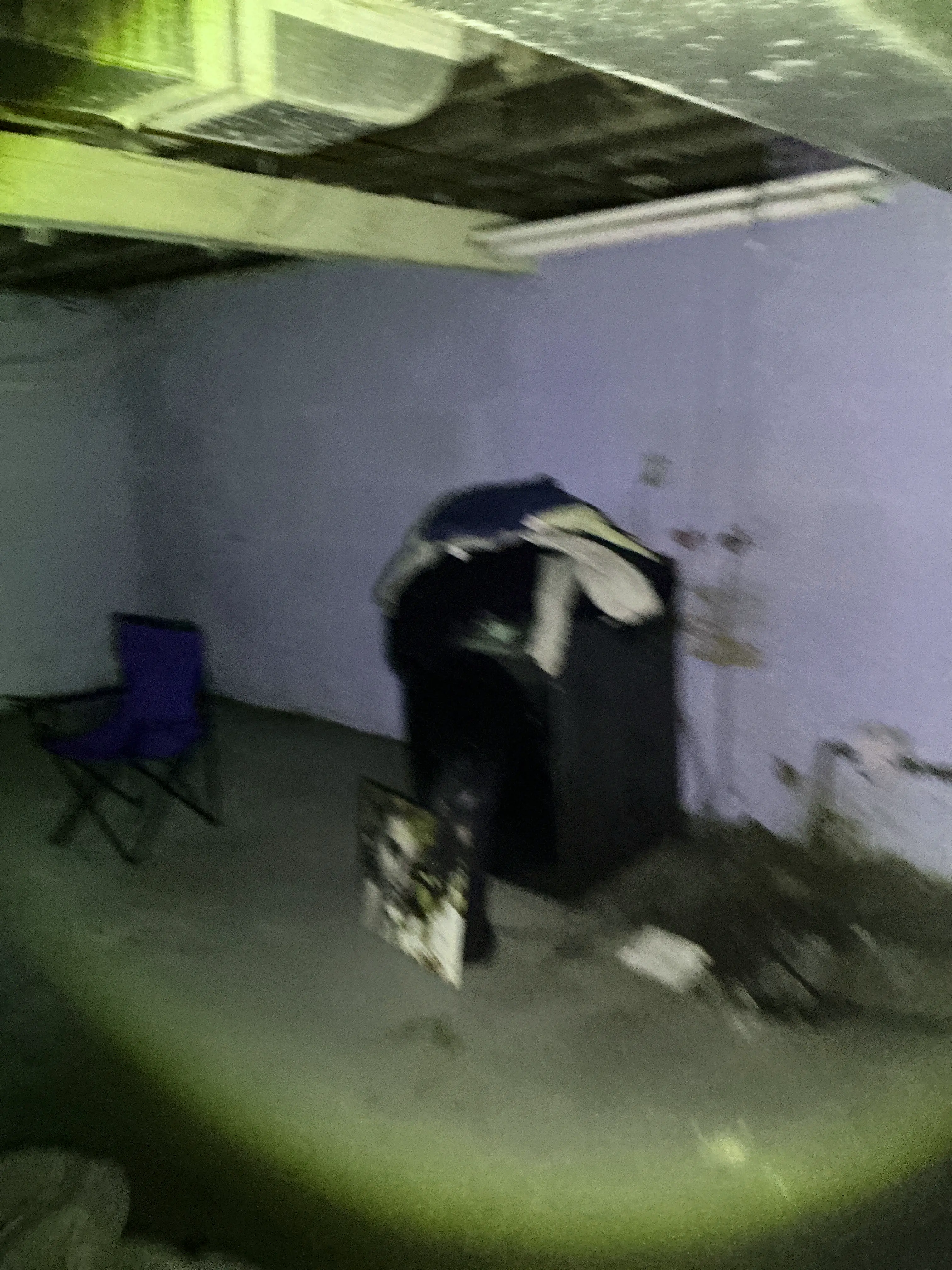 Flashlight beam illuminating a dark basement room with furniture during mold testing 2026-08-03