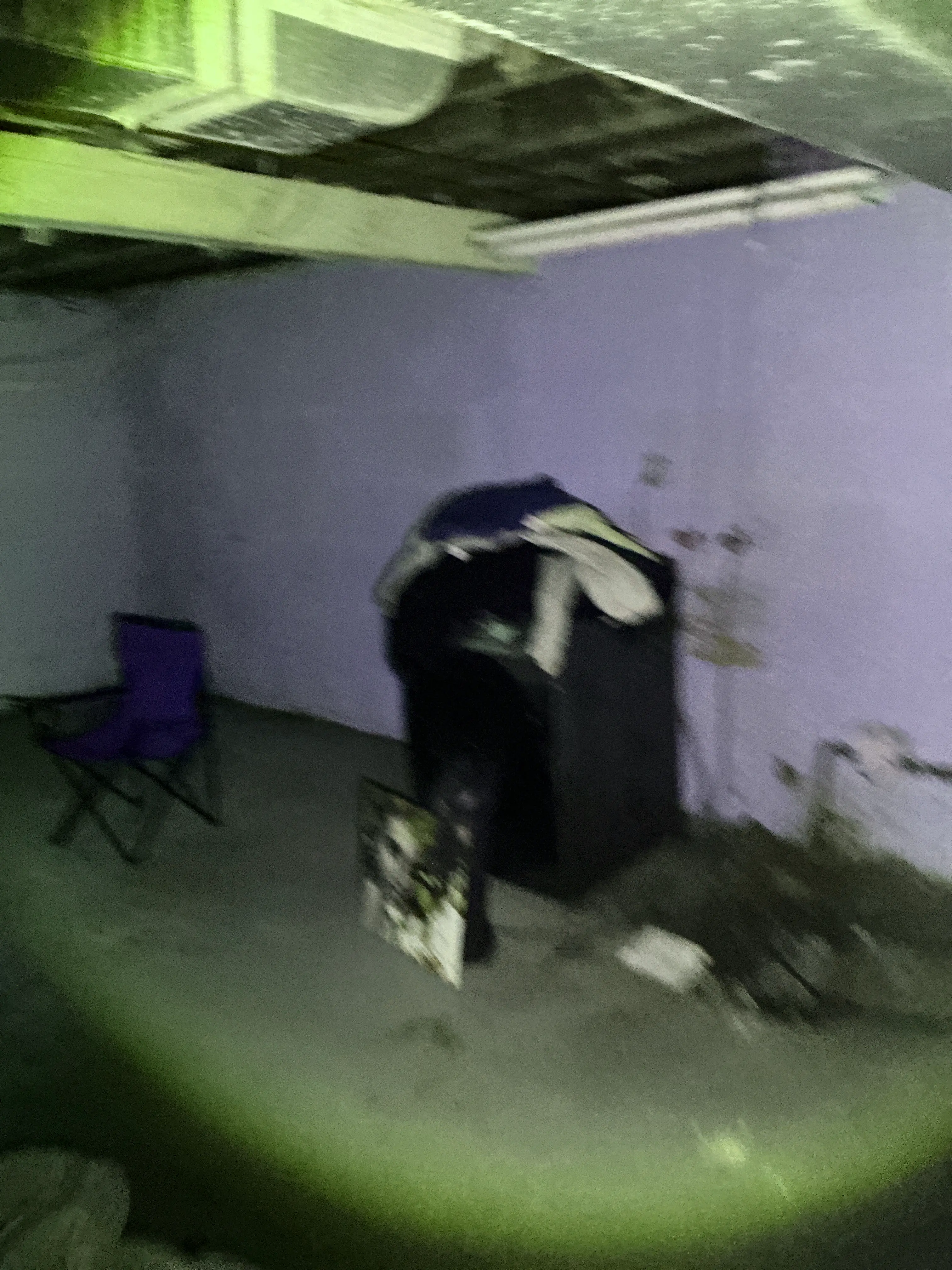 Flashlight beam illuminating a dark basement room with furniture during lead test 2026-08-05