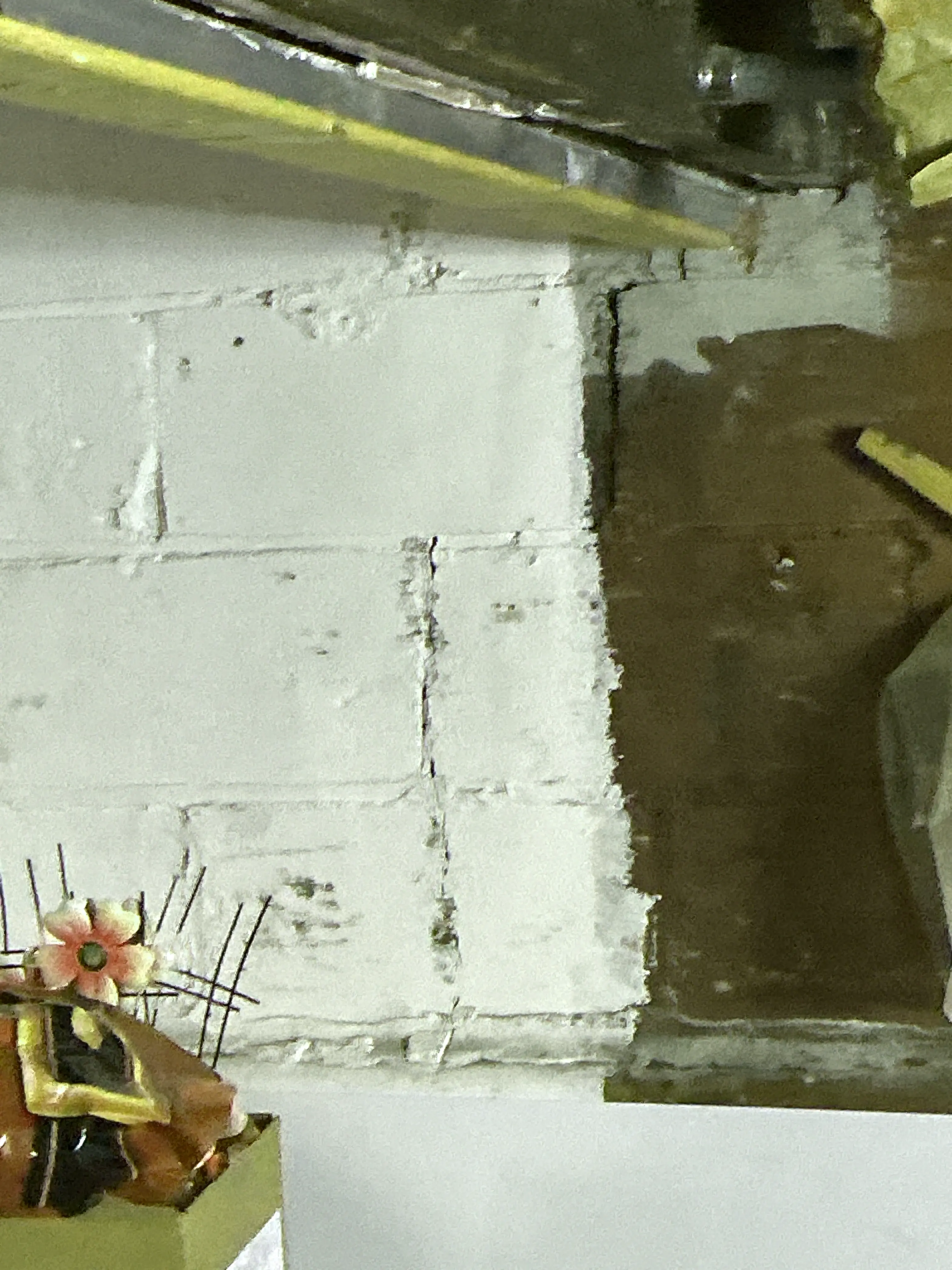 Damaged wall surface with exposed mortar and cracked plaster behind kitchen cabinet. 2026-09-01
