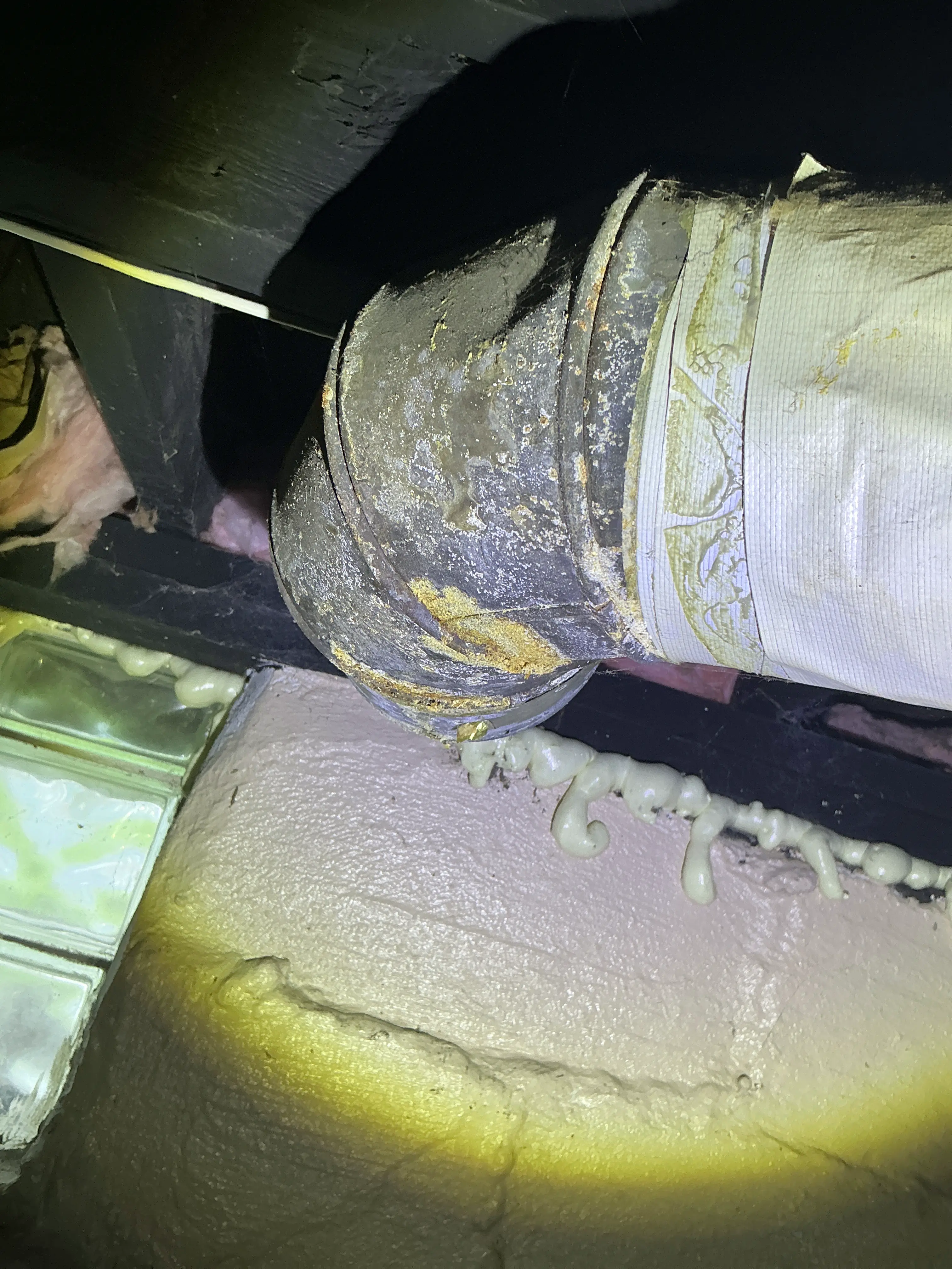 Corroded metal HVAC duct pipe with spray foam insulation in a basement crawlspace 2026-08-30