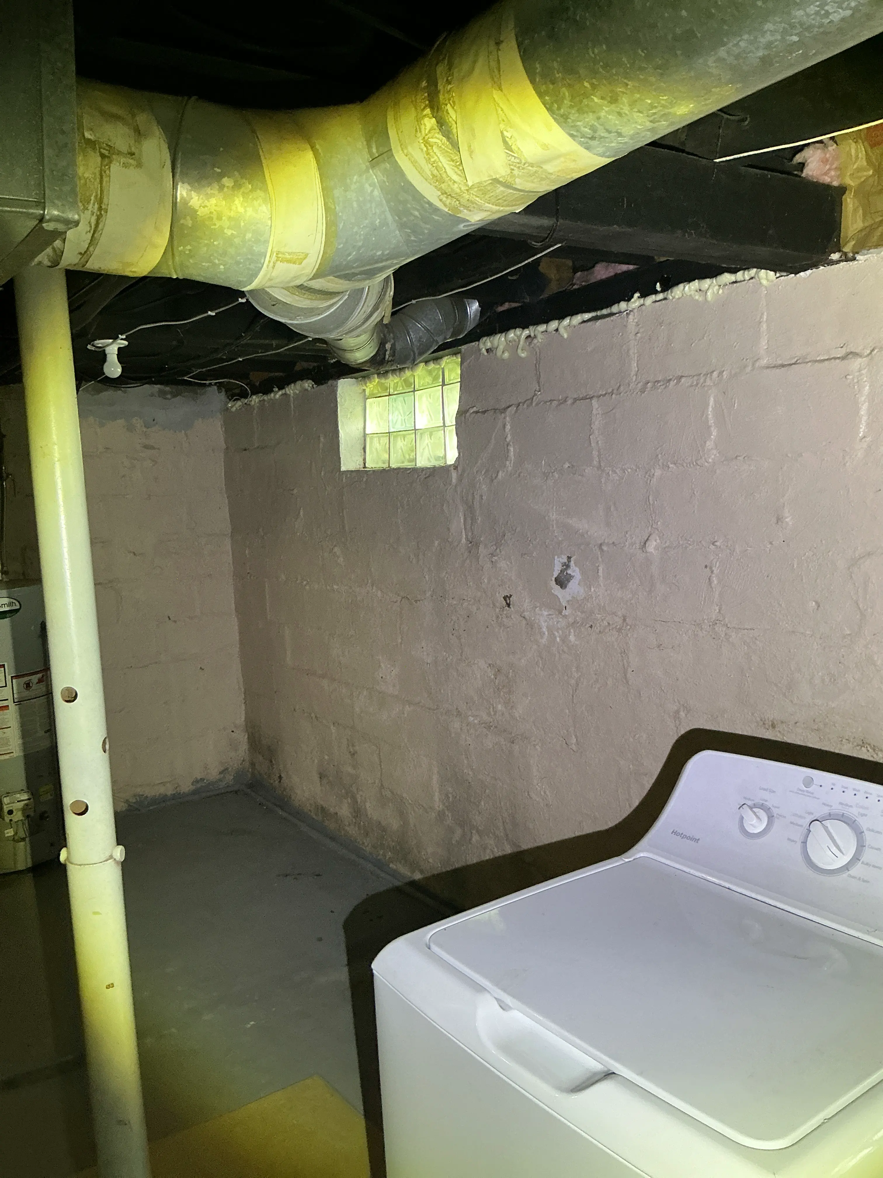 Basement indoor air quality testing showing taped ductwork and cinder block foundation wall near laundry appliance 2026-08-07