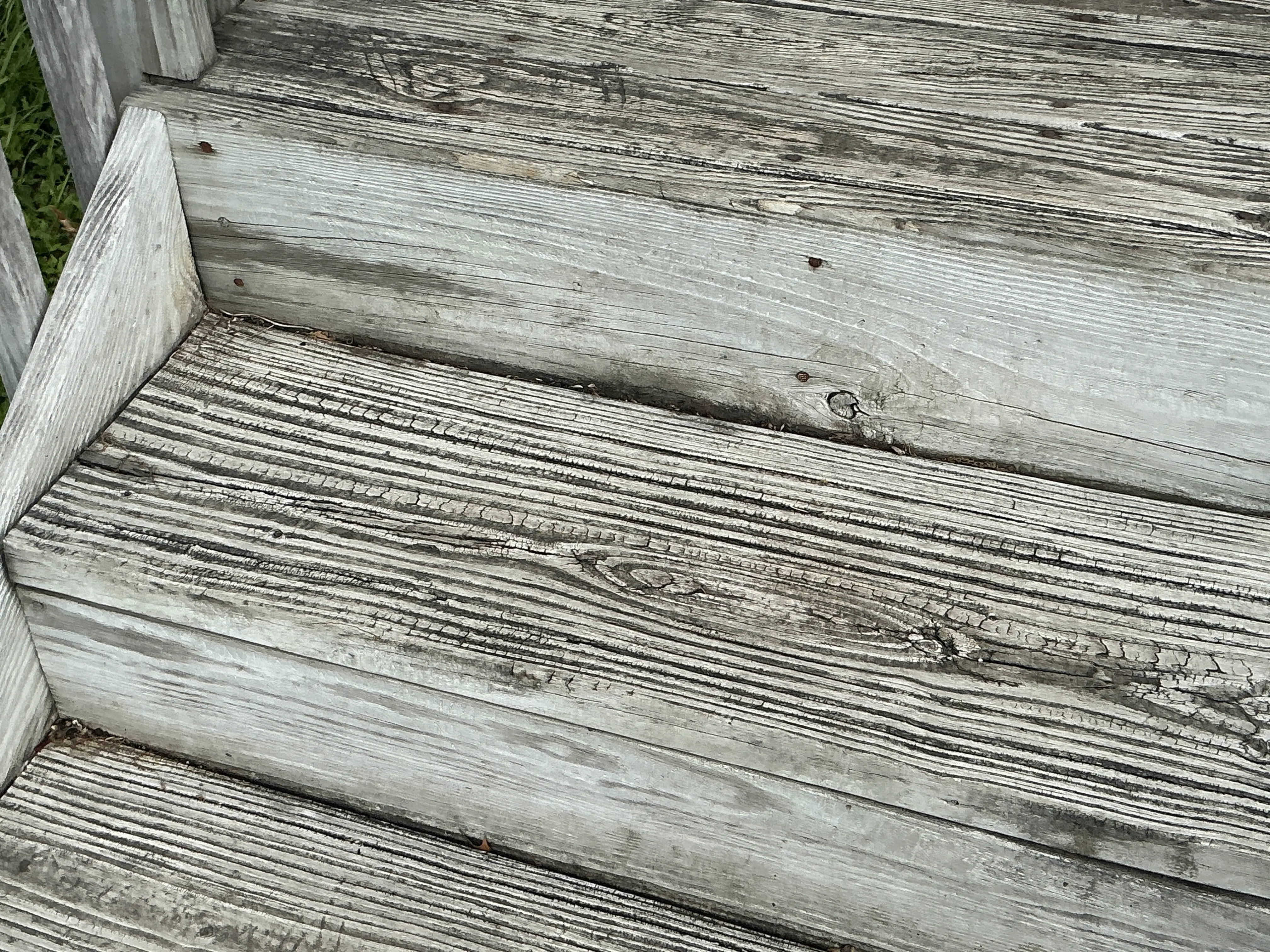 Weathered wooden deck steps with cracked grain needing repair and sealing 2026-08-16