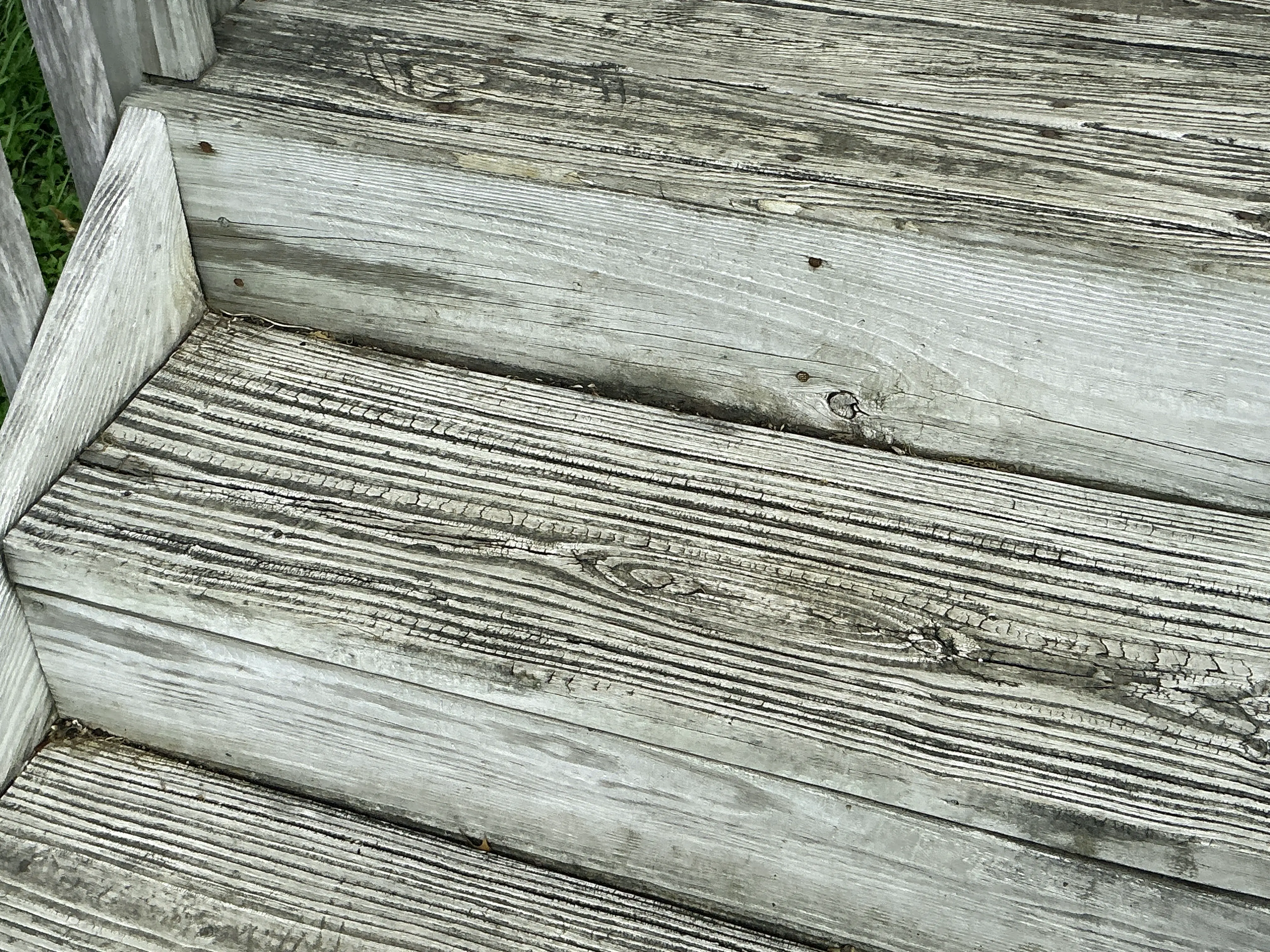 Weathered wooden deck steps with cracked grain needing repair and sealing 2026-08-08