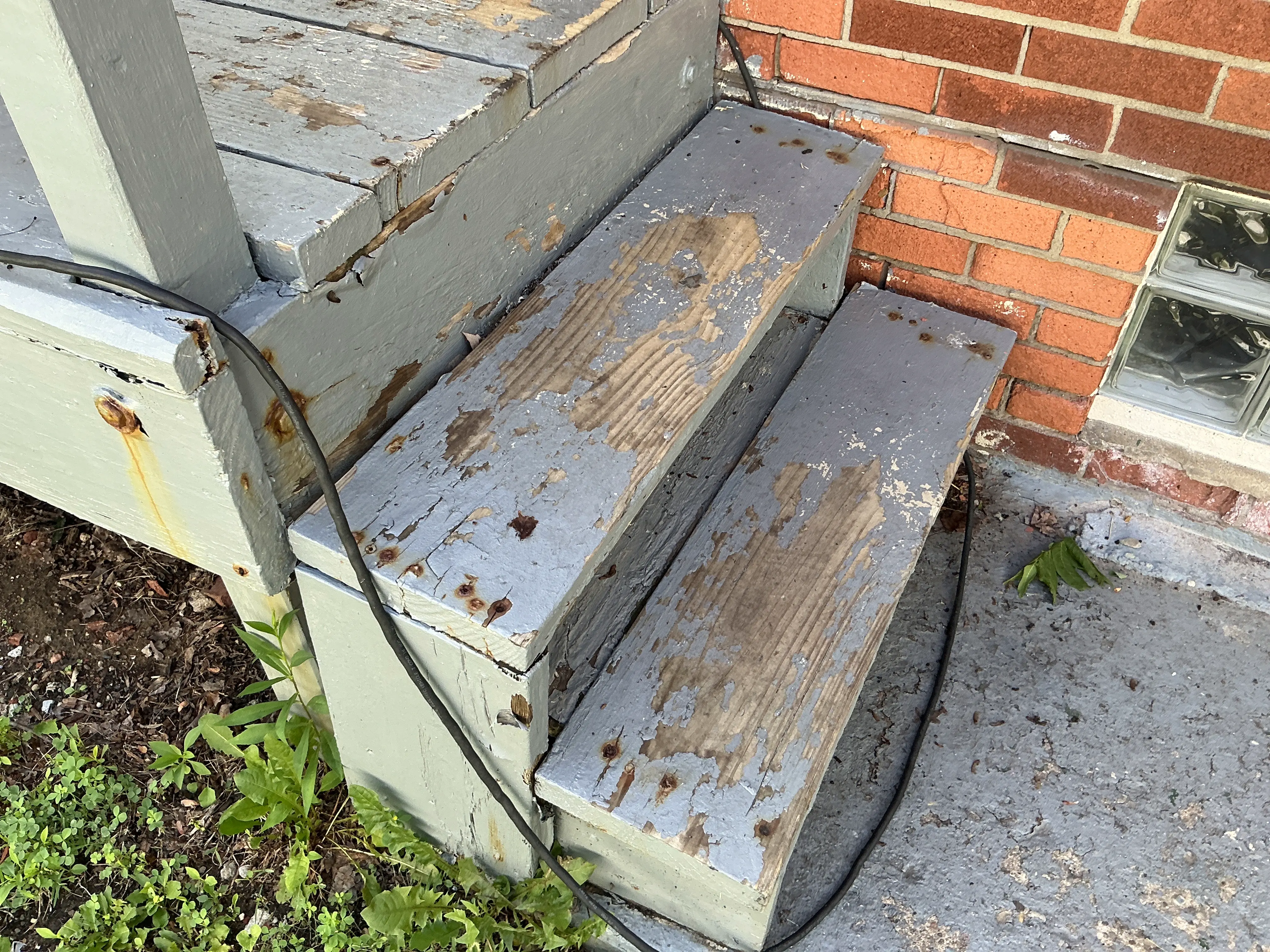 Peeling paint and weathered wood on exterior porch steps needing repair and repainting 2026-07-22