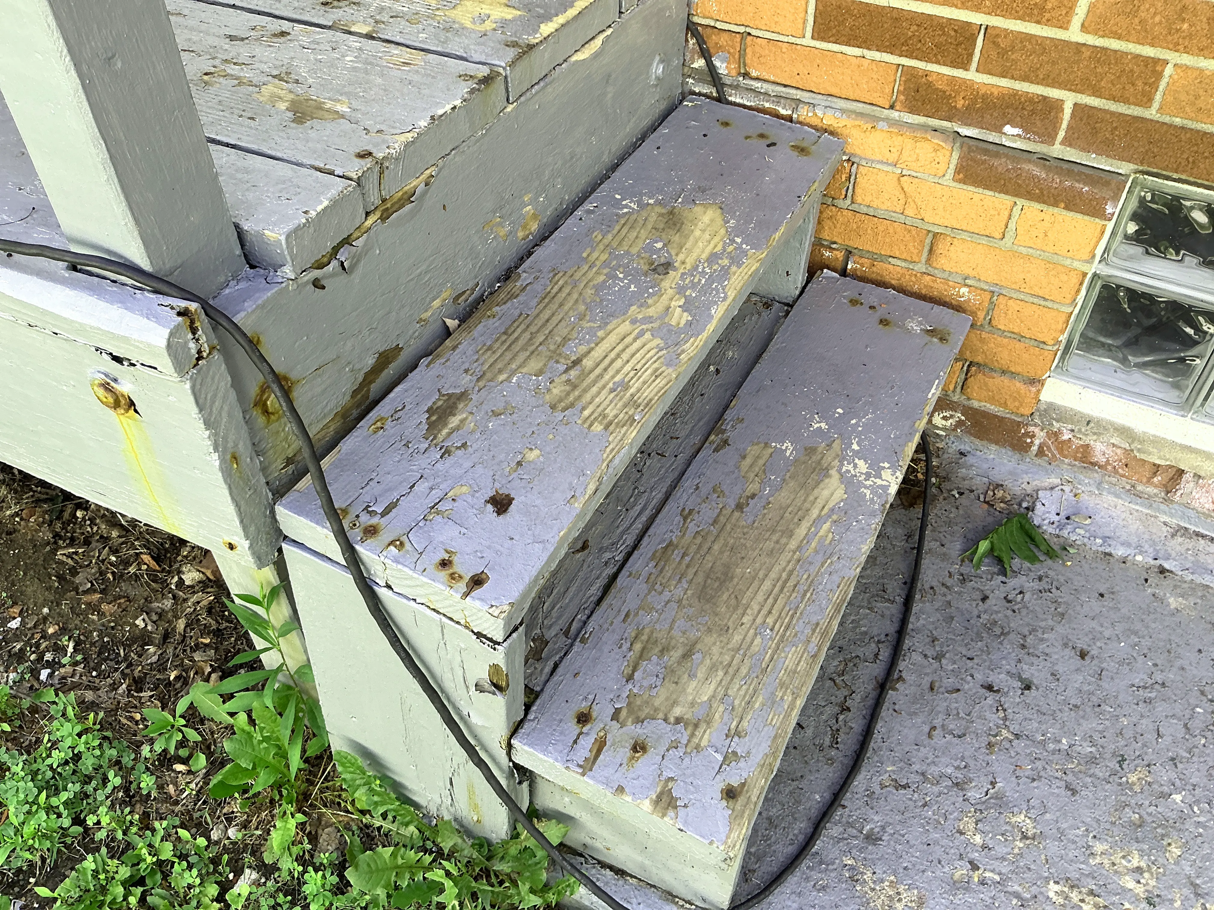 Peeling paint and weathered wood on exterior porch steps needing repair and repainting 2026-08-24