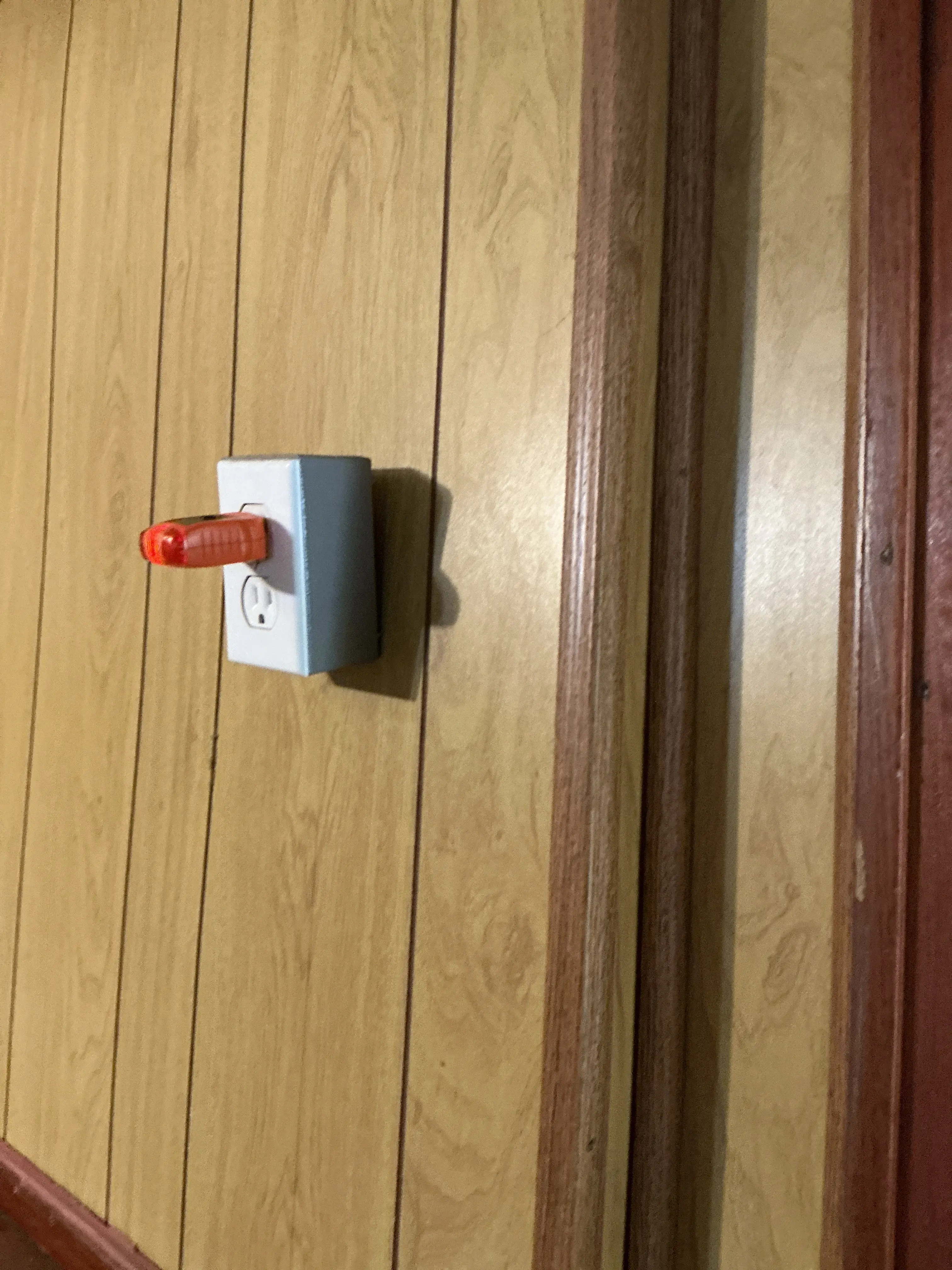 Plug-in electrical outlet tester inserted into a wall receptacle on wood paneling during a home inspection 2026-09-01