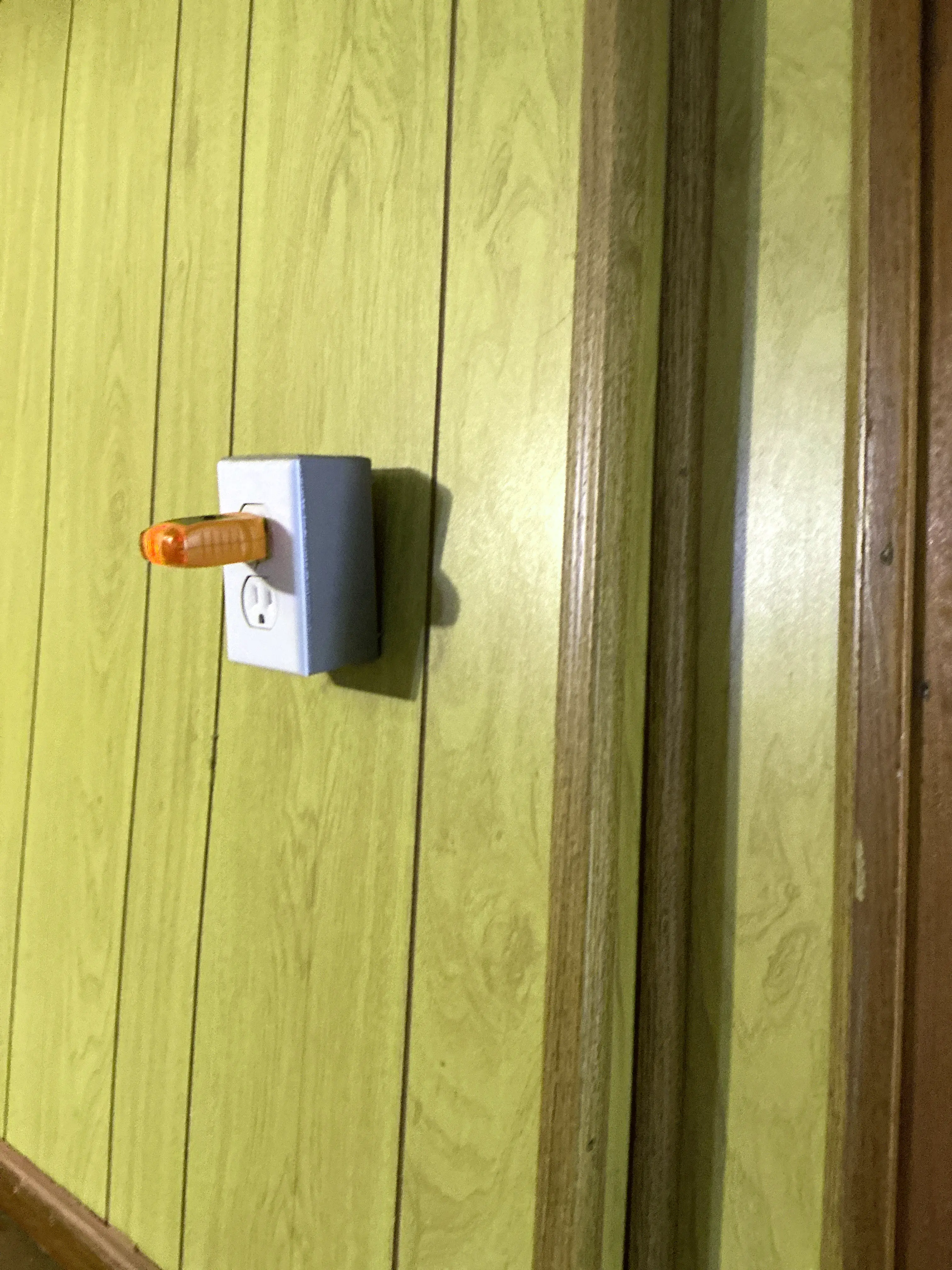 Plug-in electrical outlet tester inserted into a wall receptacle on wood paneling during a mold testing 2026-08-15