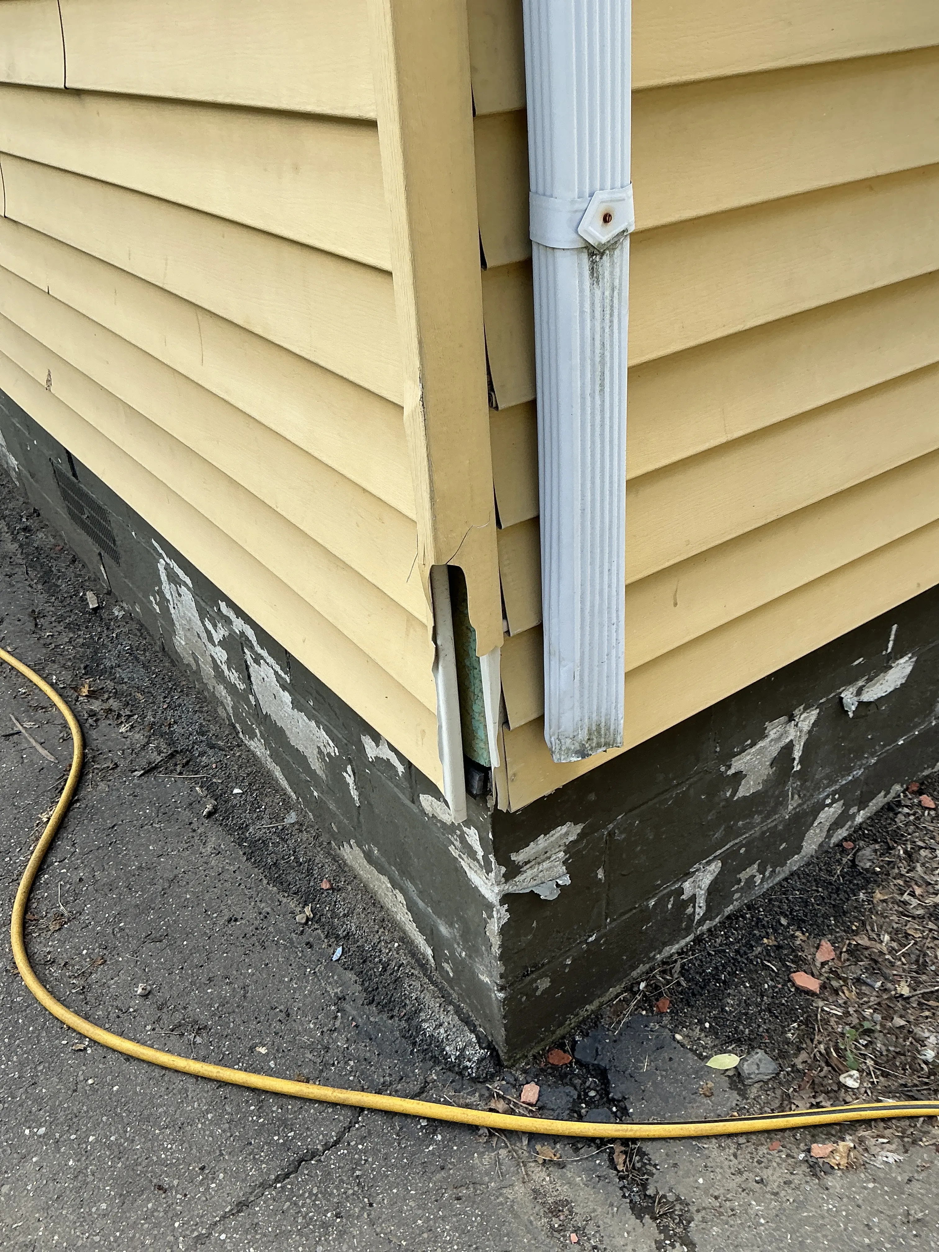 Damaged yellow vinyl siding trim and cracked exterior corner during a lead test 2026-08-05