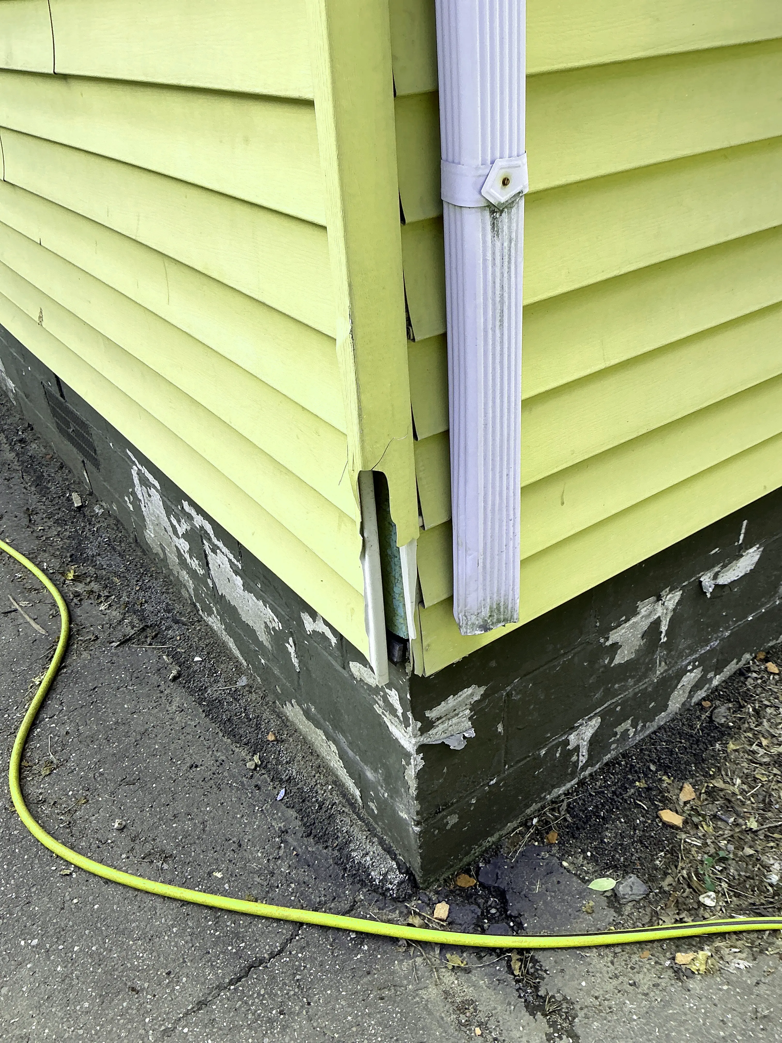 Damaged yellow vinyl siding trim and cracked exterior corner during a mold inspection 2026-08-11