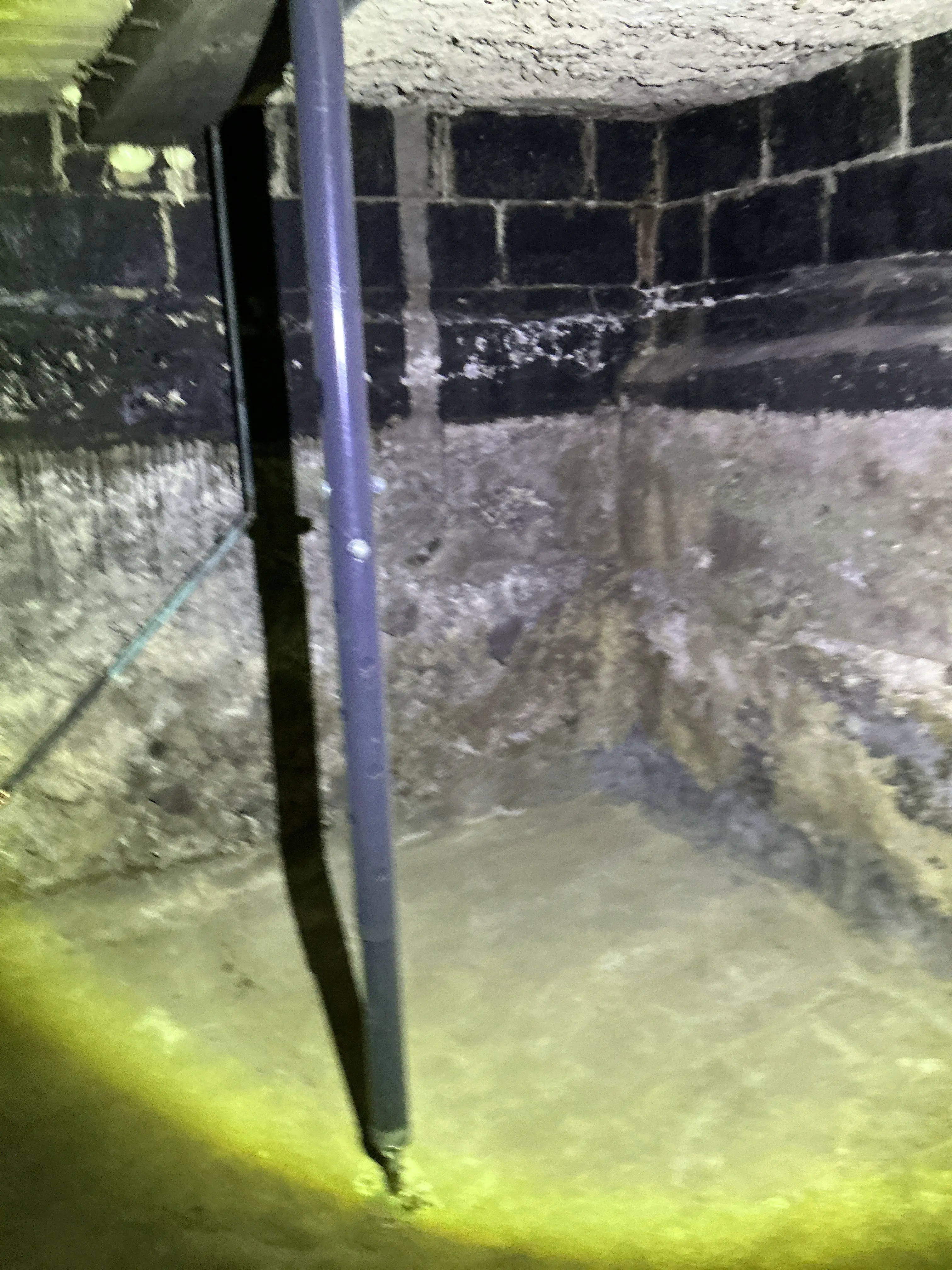 Home inspection photo of utility pipe in dark crawlspace illuminated by flashlight 2026-07-12