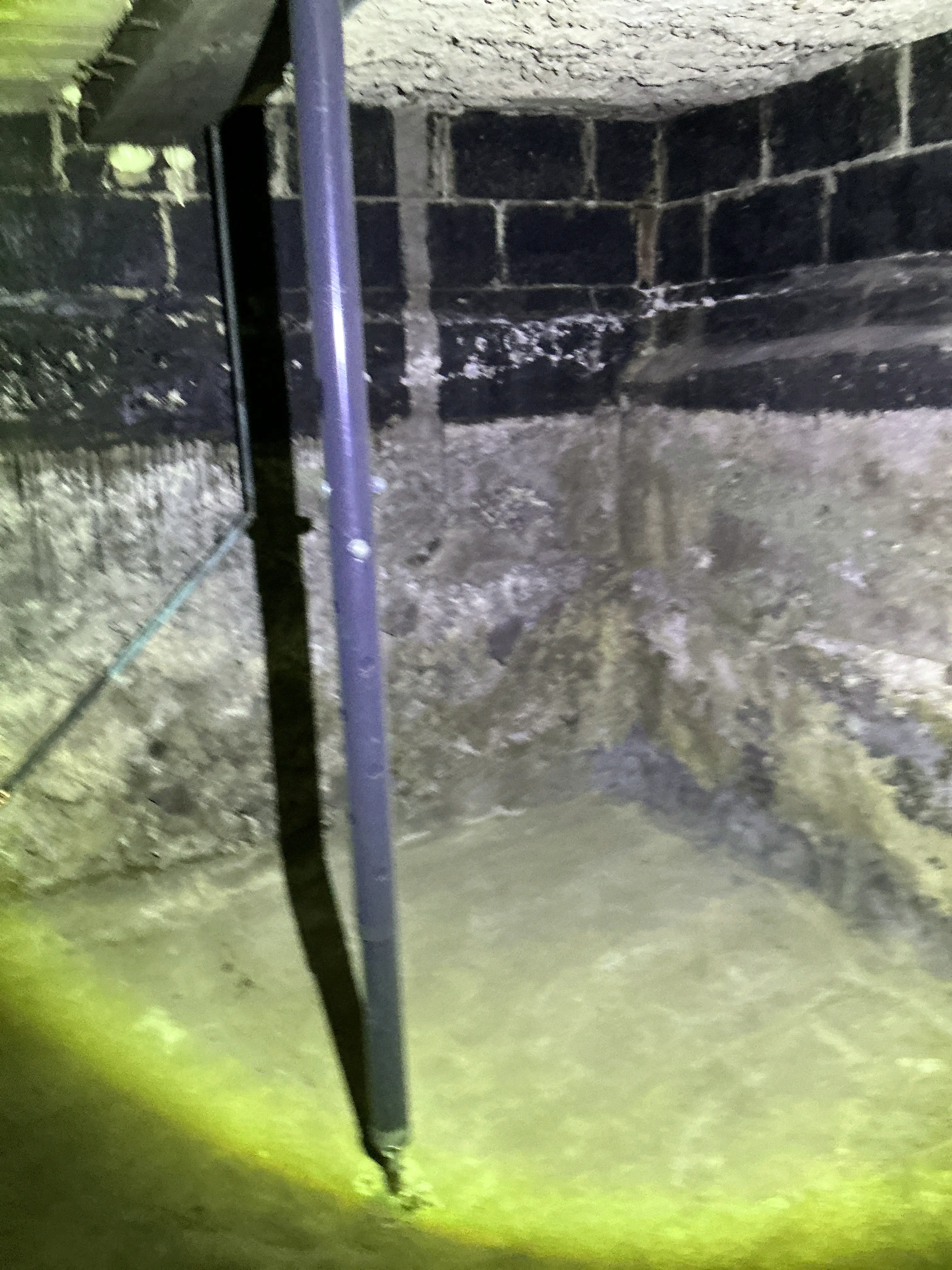 Home inspection photo of utility pipe in dark crawlspace illuminated by flashlight 2026-08-25