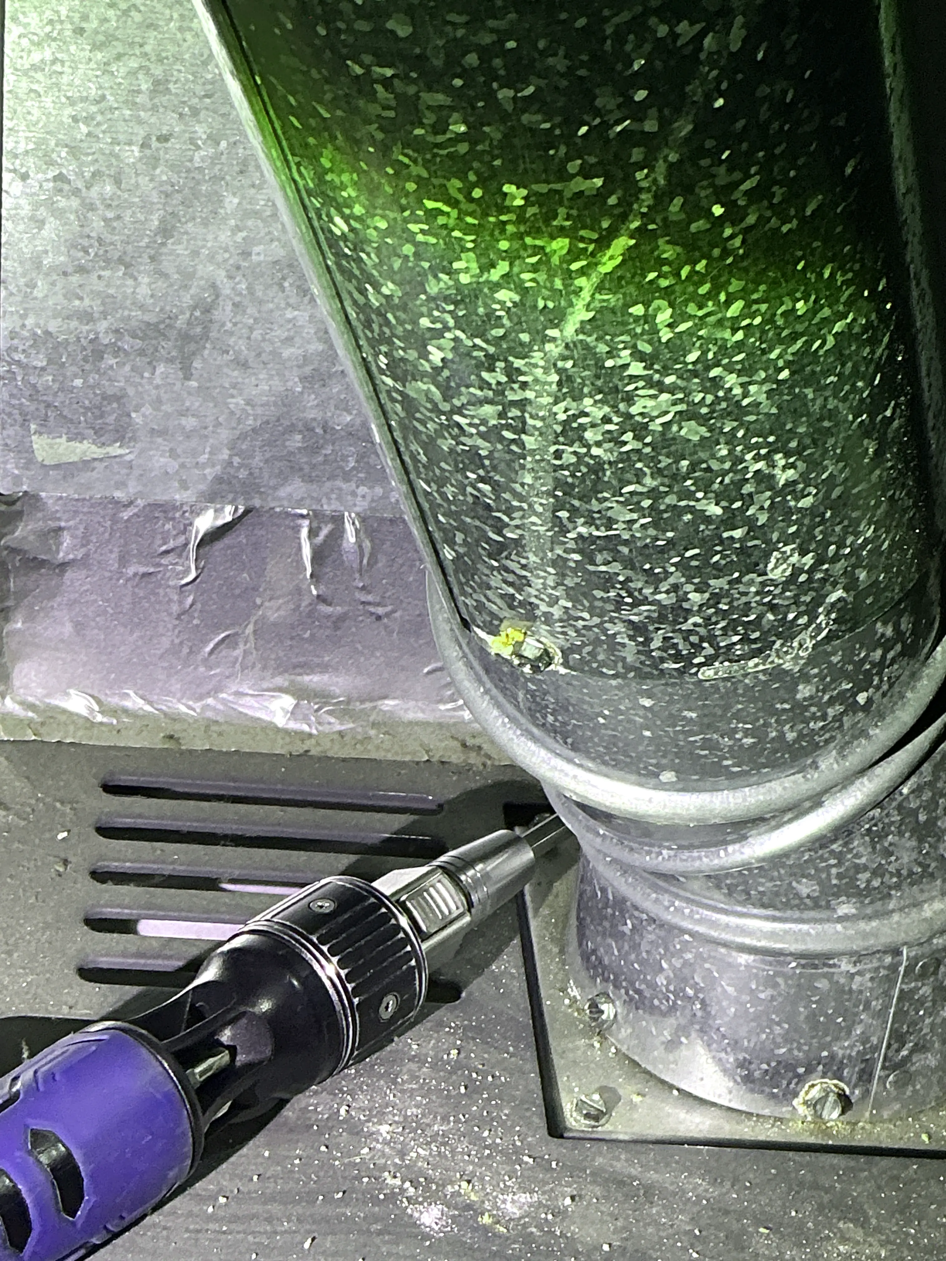 Galvanized metal exhaust flue pipe connection on heating unit inspected with tool 2026-08-24