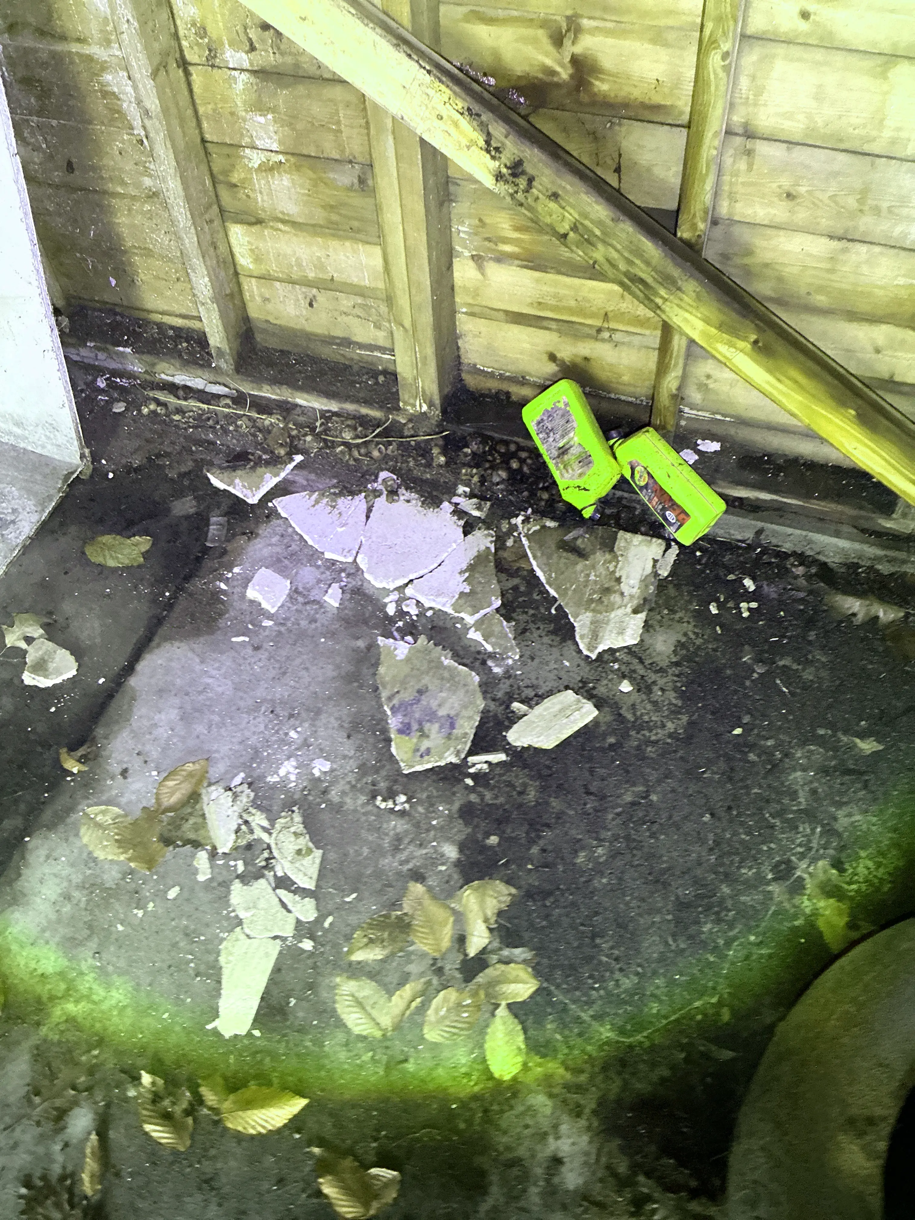 Broken drywall fragments and debris on concrete floor next to wooden wall framing 2026-07-14