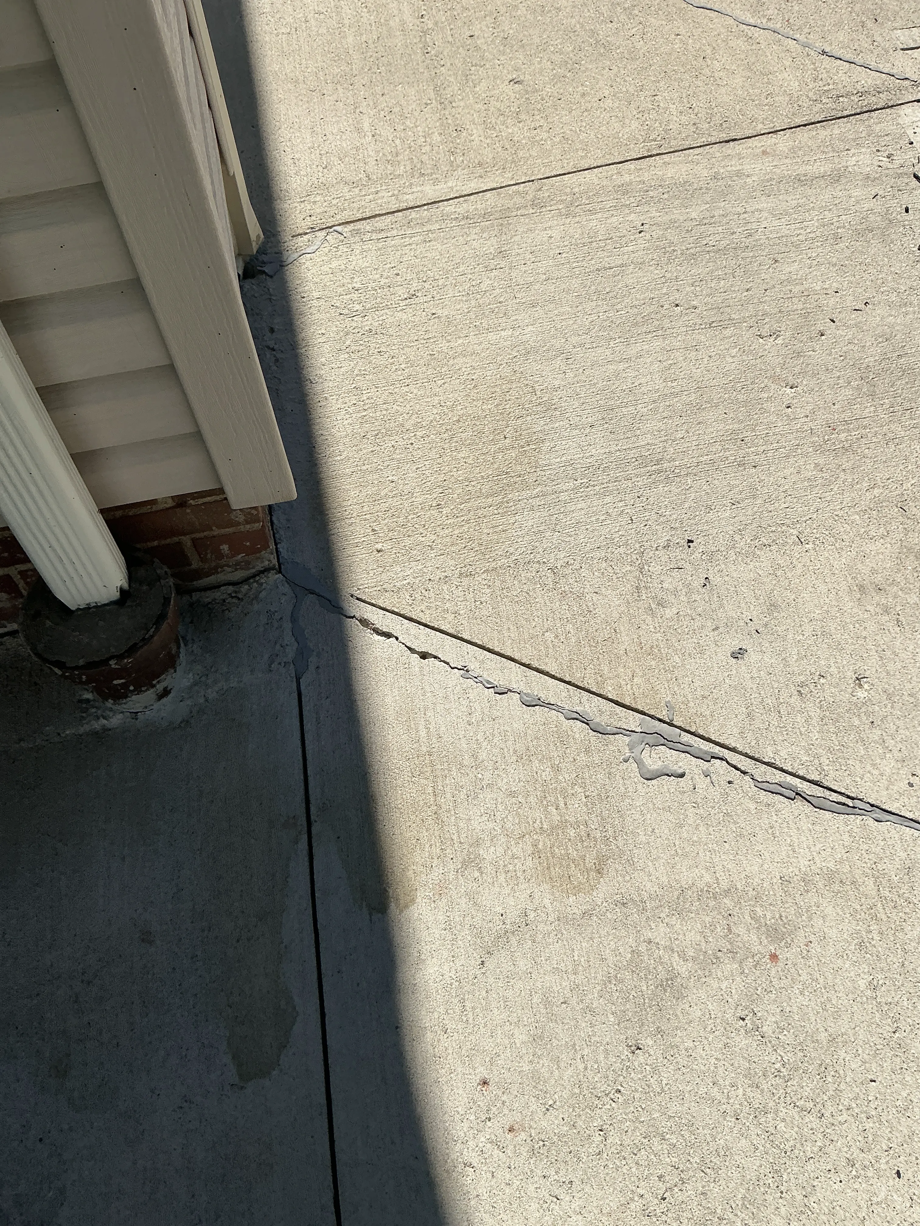 Sealed crack in outdoor concrete slab near building foundation 2026-07-05