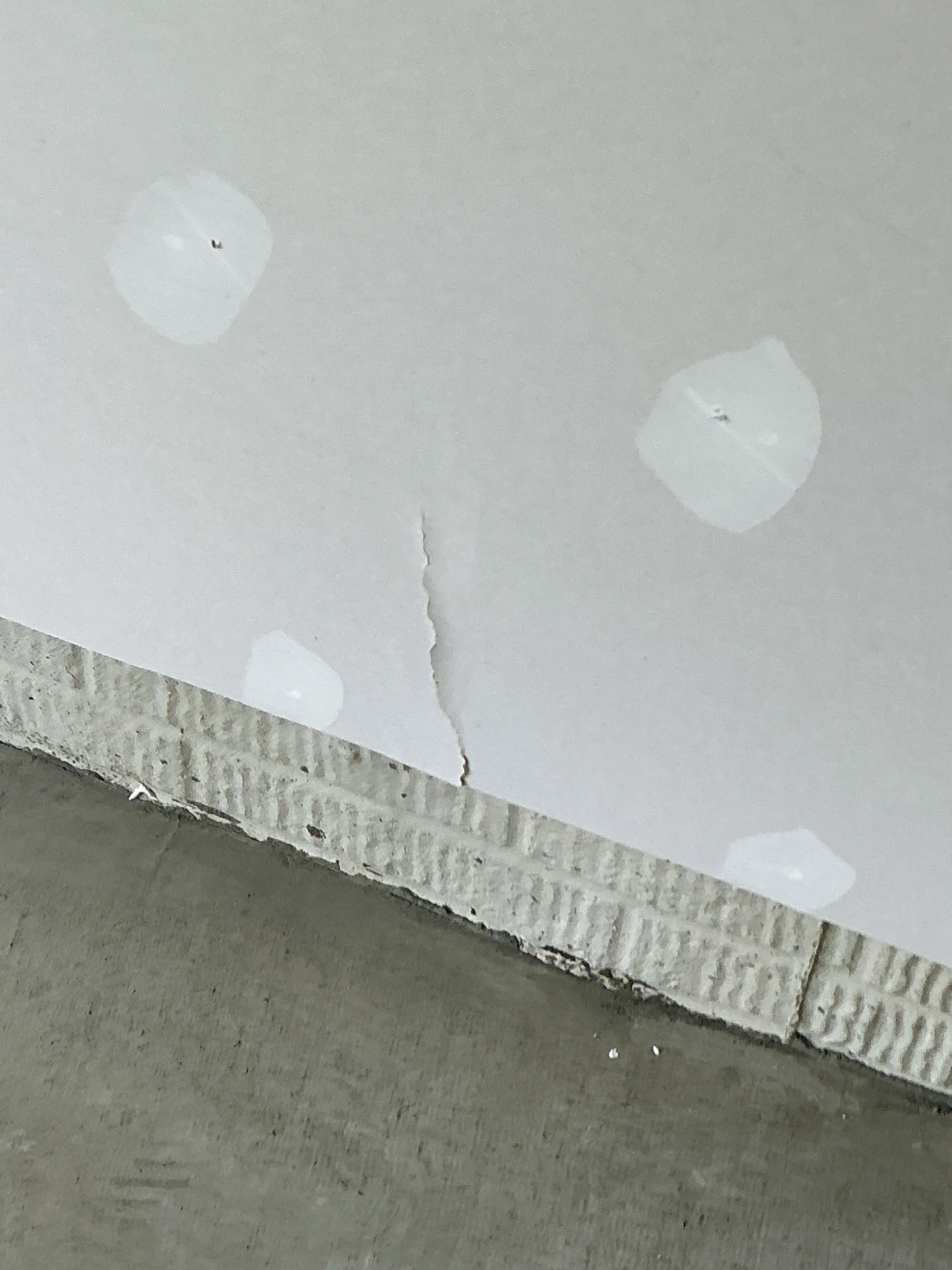 Visible crack in drywall panel near patched screw holes requiring repair 2026-08-25