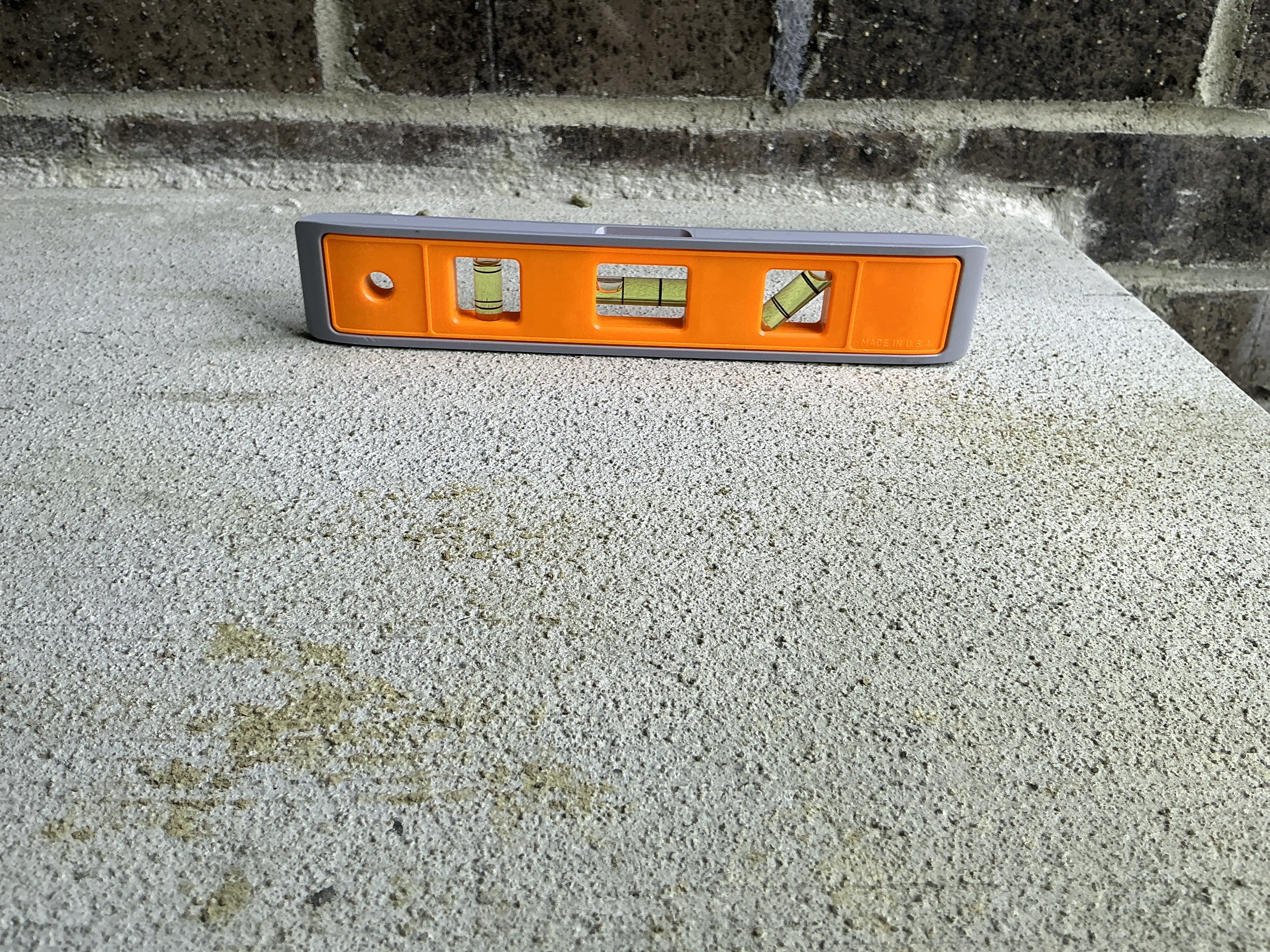 Torpedo level sitting on concrete surface during mold inspection to verify slope 2026-08-24