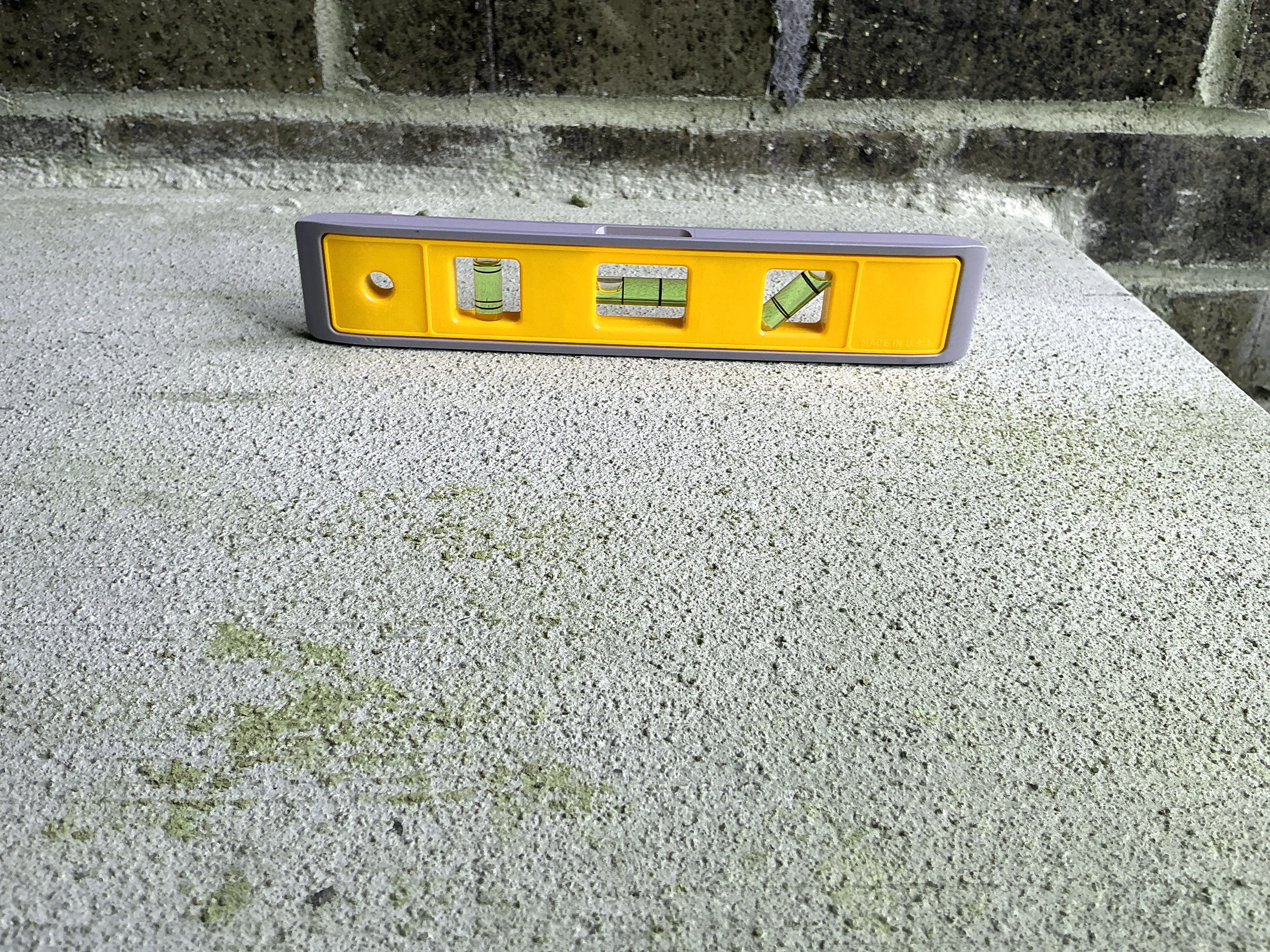 Torpedo level sitting on concrete surface during general inspection to verify slope 2026-07-05