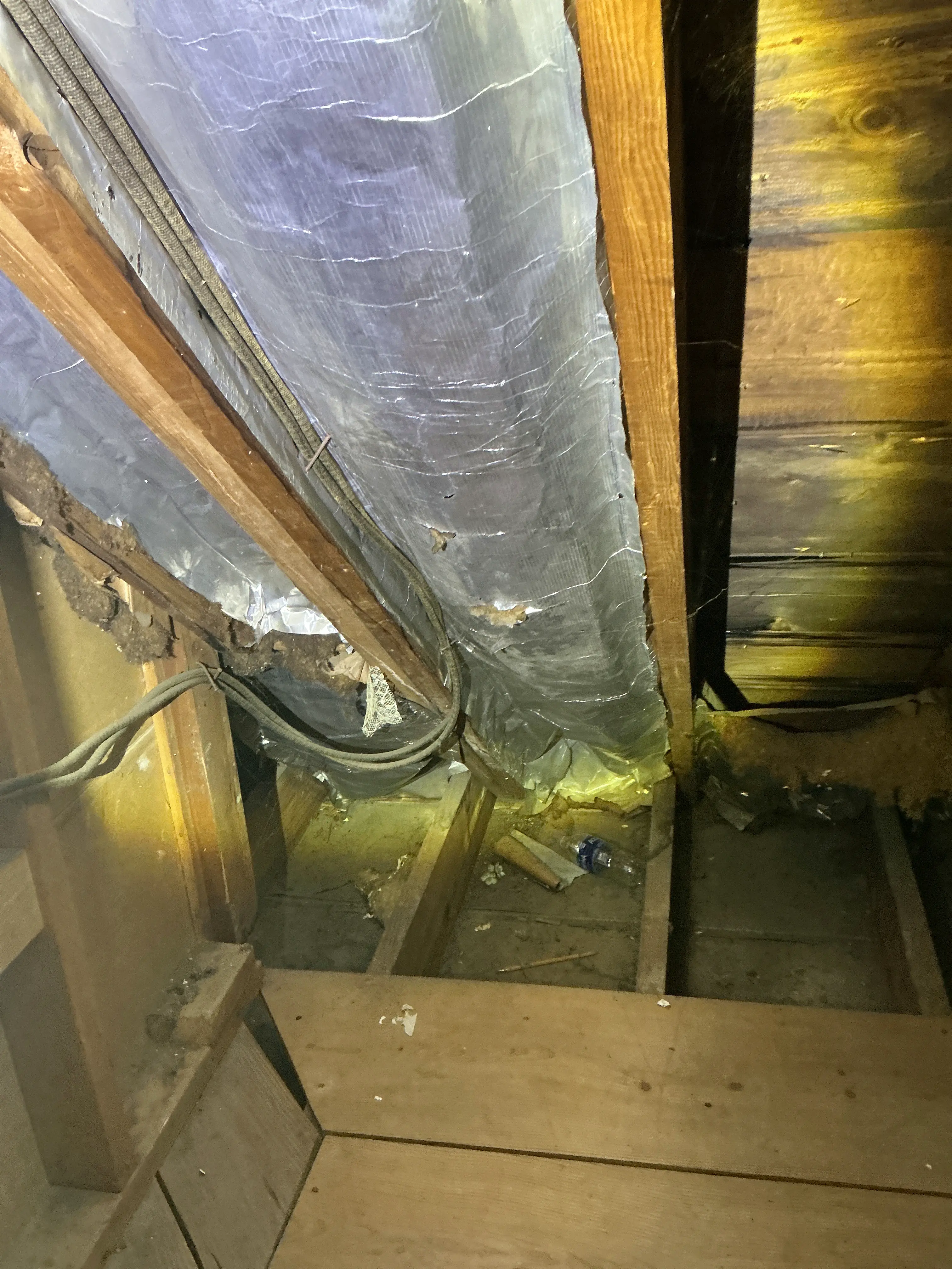 Insulated flexible HVAC duct and electrical cables running along wooden joists in an attic space 2026-08-03